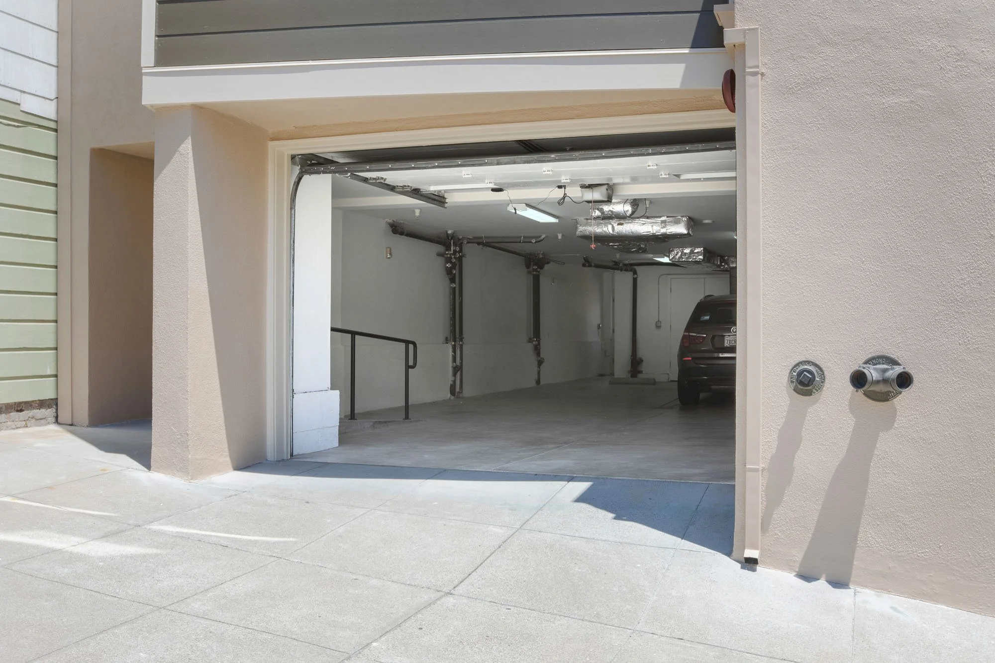 Street-level view of a private urban garage with an open roll-up door, providing secure off-street parking in a San Francisco neighborhood.