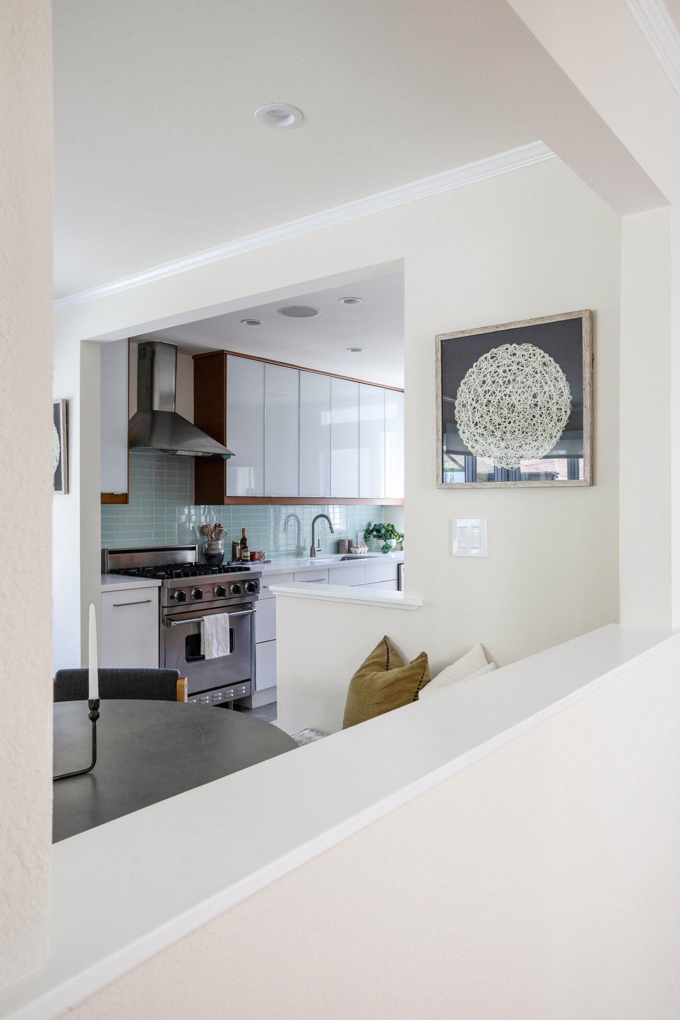 Architectural cutout between the dining room and kitchen, highlighting the stainless steel Viking range and glass tile backsplash.