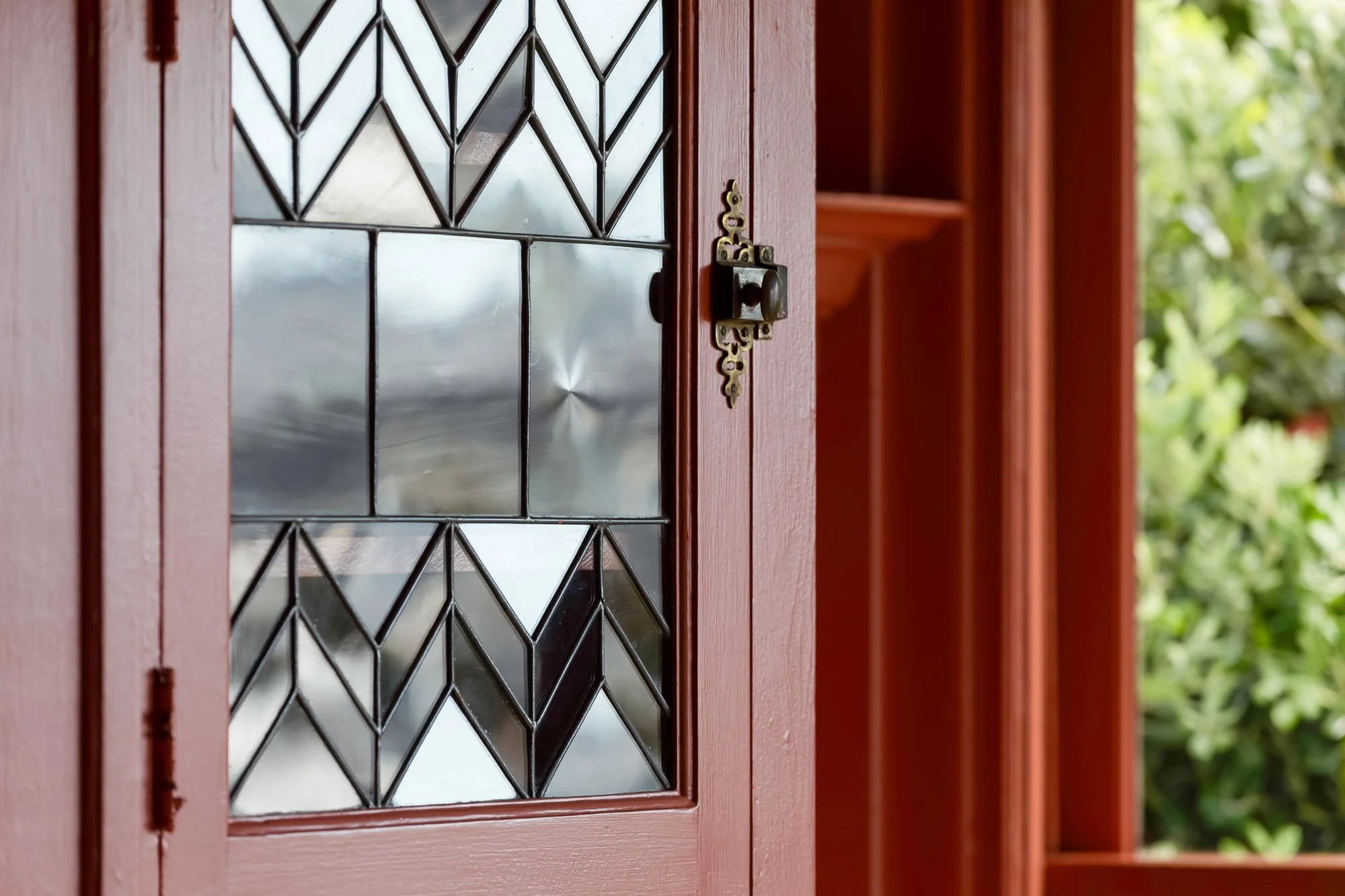 Original Victorian leaded-glass cabinet door with geometric chevron pattern and antique brass latch hardware in Presidio Heights Victorian flat, San Francisco