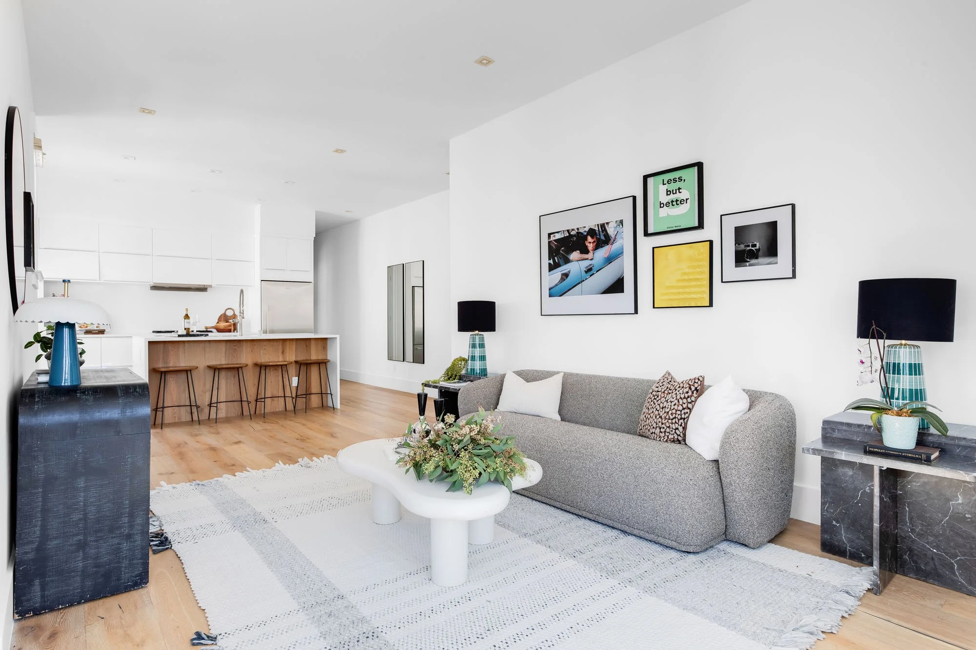 Spacious open-plan living area with modern furniture, a large white area rug, and light oak hardwood flooring.