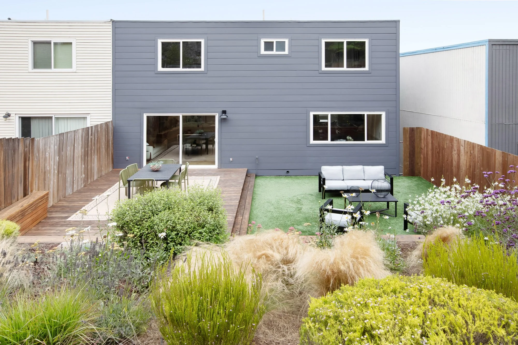 Rear yard at 75 Aloha Avenue in Golden Gate Heights viewed from the planted hillside, with drought-tolerant grasses in the foreground and the deck and lawn below.