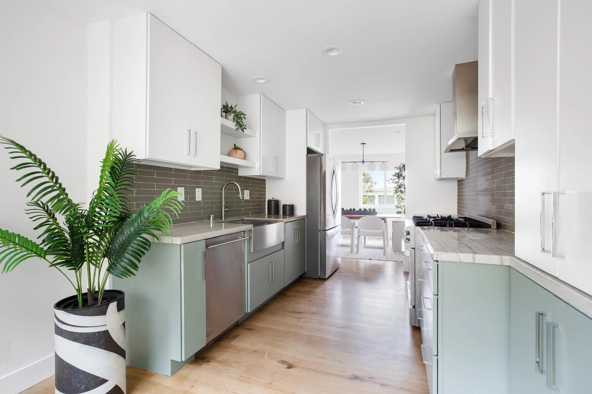 Refreshed kitchen at 75 Aloha Avenue, San Francisco, with sage-green cabinetry, stone counters, a green tile backsplash, and a gas range under a stainless hood.