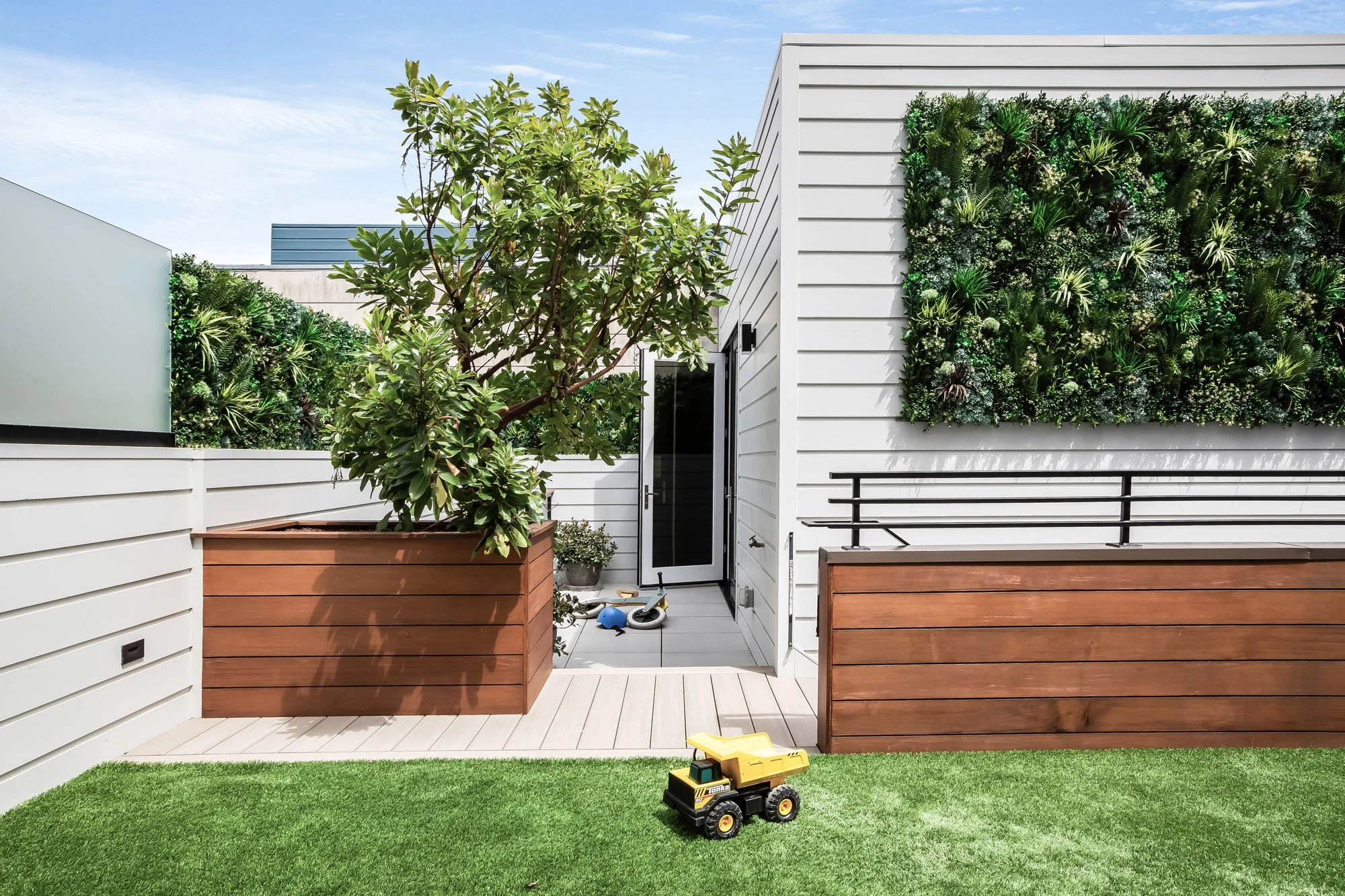 Private rooftop garden at 1647 Sanchez featuring a vertical living green wall, modern white siding, and a seamless indoor-outdoor play space.