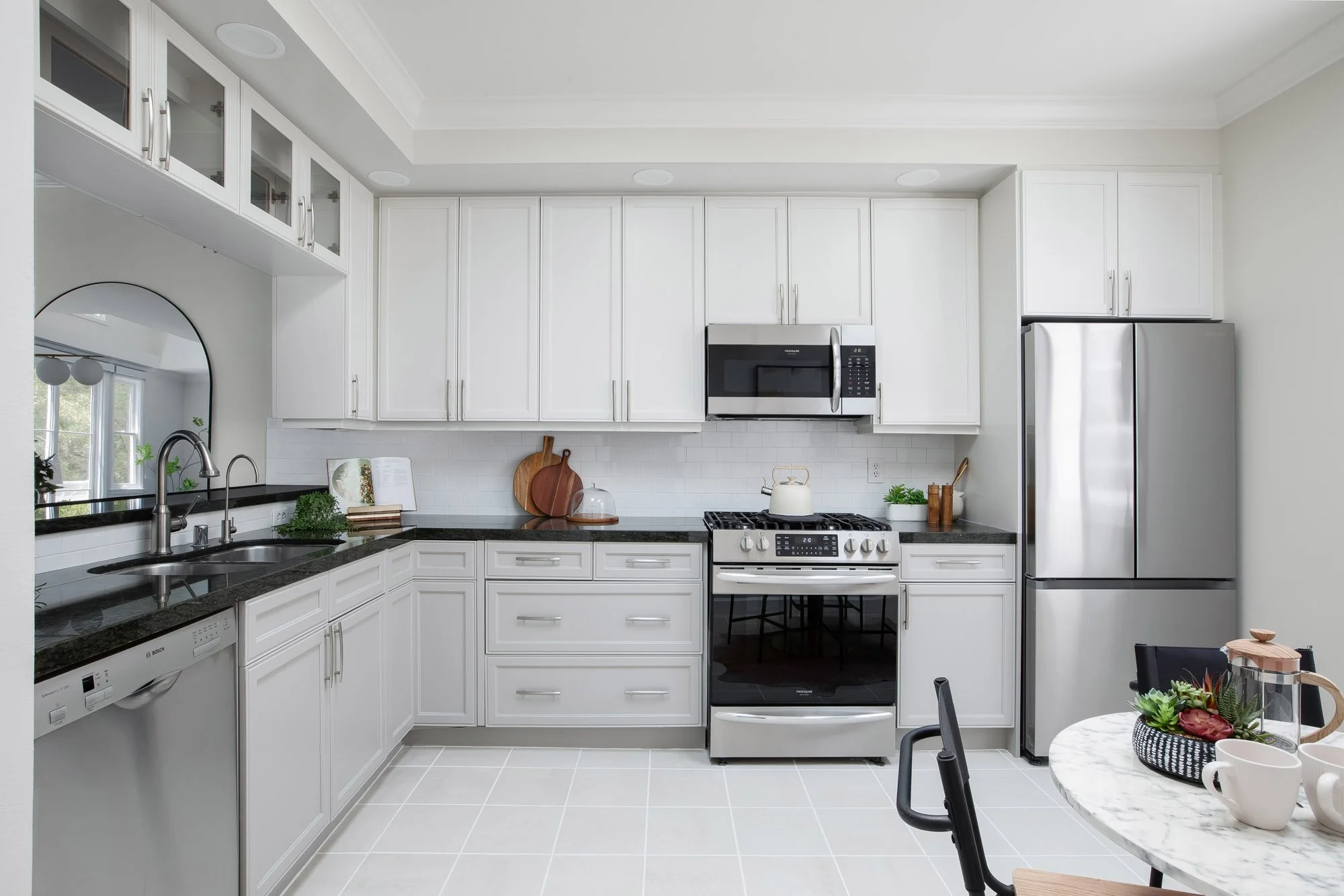 Renovated kitchen at 2172 Fell Street San Francisco with white shaker cabinets, dark granite countertops, stainless steel gas range, Bosch dishwasher, subway tile backsplash, and marble breakfast table
