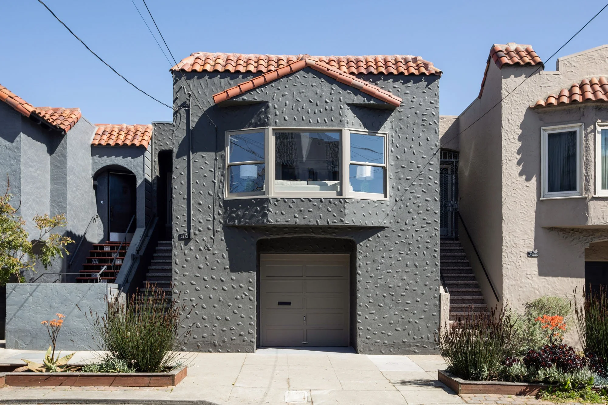 Symmetrical front elevation of 2872 25th St showing the architectural pebble-dash texture, bay window, and integrated garage in San Francisco.