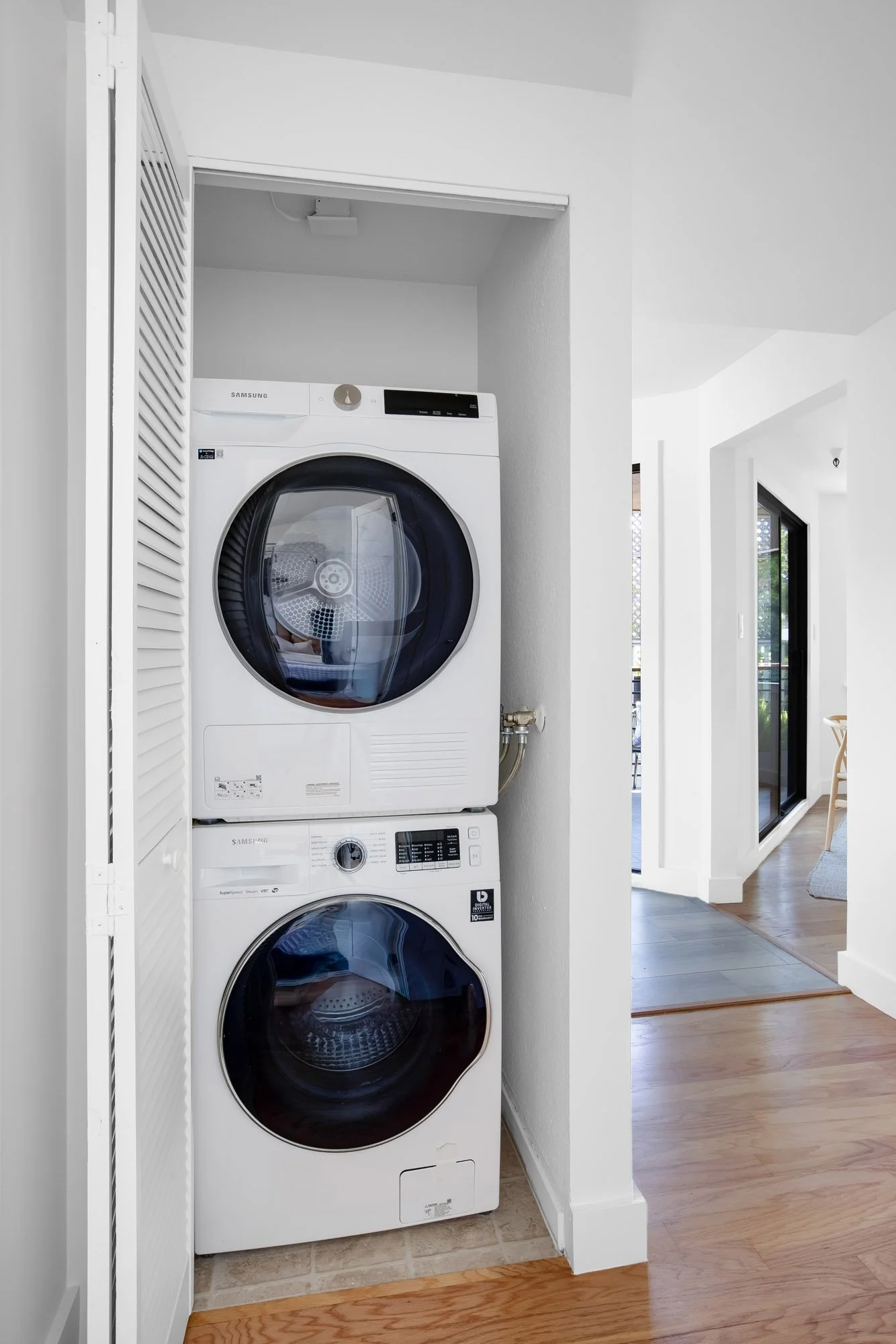 In-unit Samsung stacked washer and dryer in a closet at 932 Broderick Street #2, with hallway and balcony views beyond.