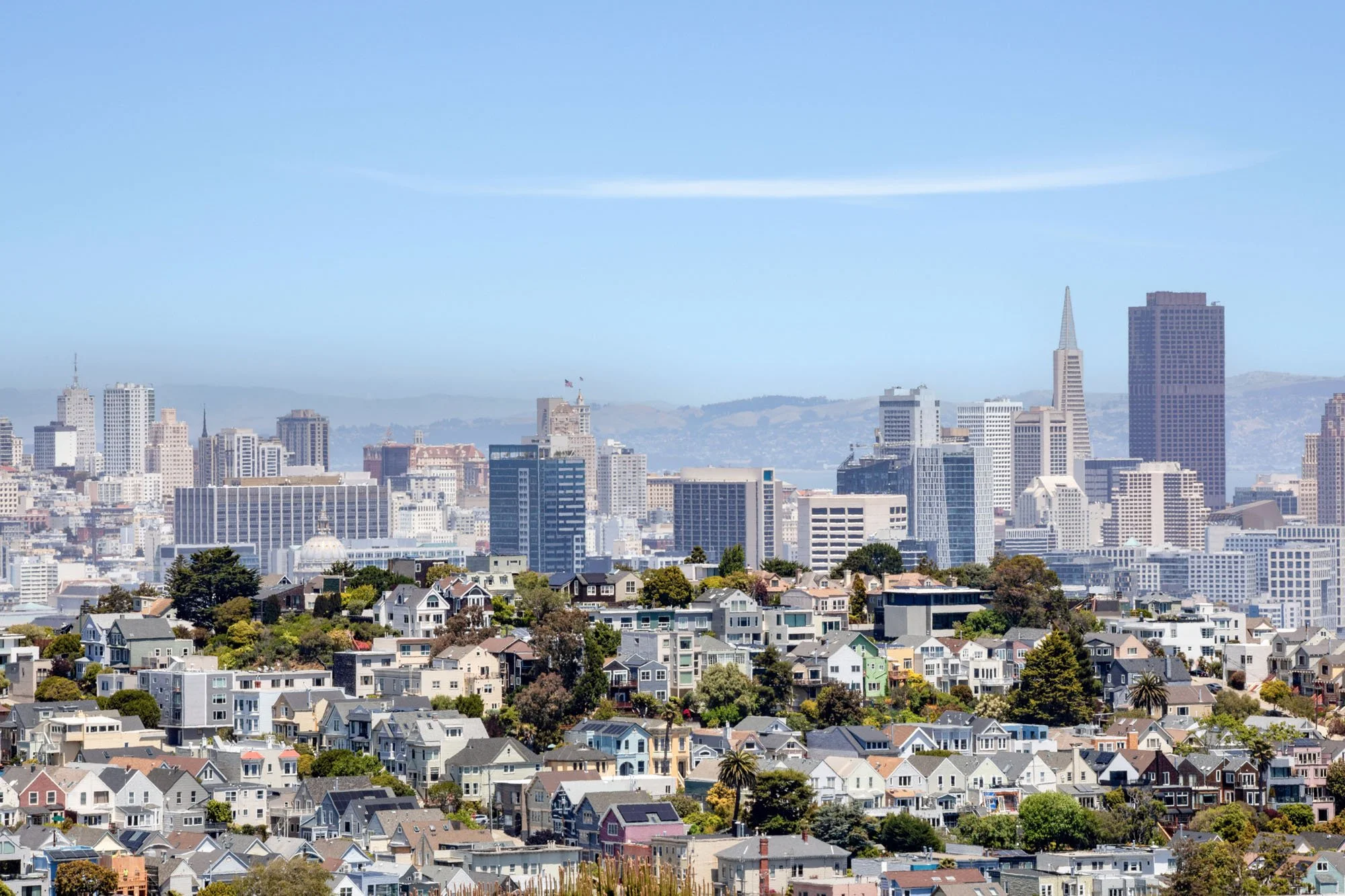A wide-angle panoramic view of the San Francisco city skyline and rolling hills from living room of 773 Duncan Street, featuring clear views of the Bay.
