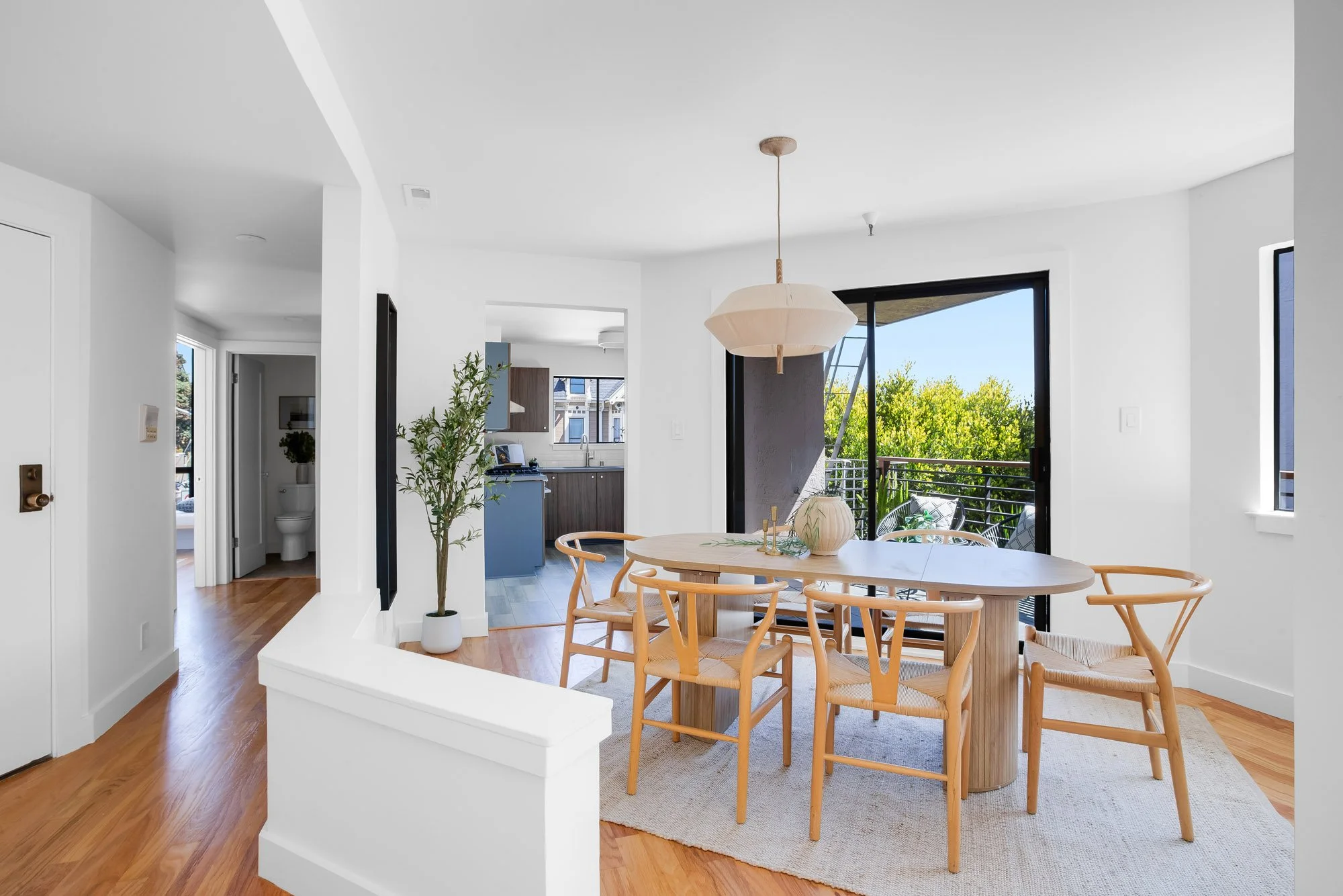 Dining area at 932 Broderick Street #2 with sliding glass doors to a private balcony, open sightline to the renovated walnut kitchen and a hallway powder room.