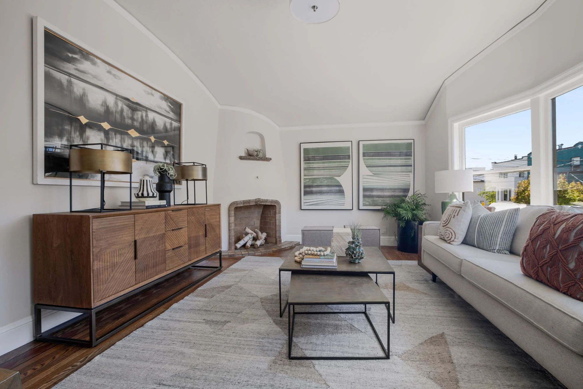 Modern living room featuring a classic fireplace, designer wood sideboard, and abstract wall art in a renovated San Francisco residence.