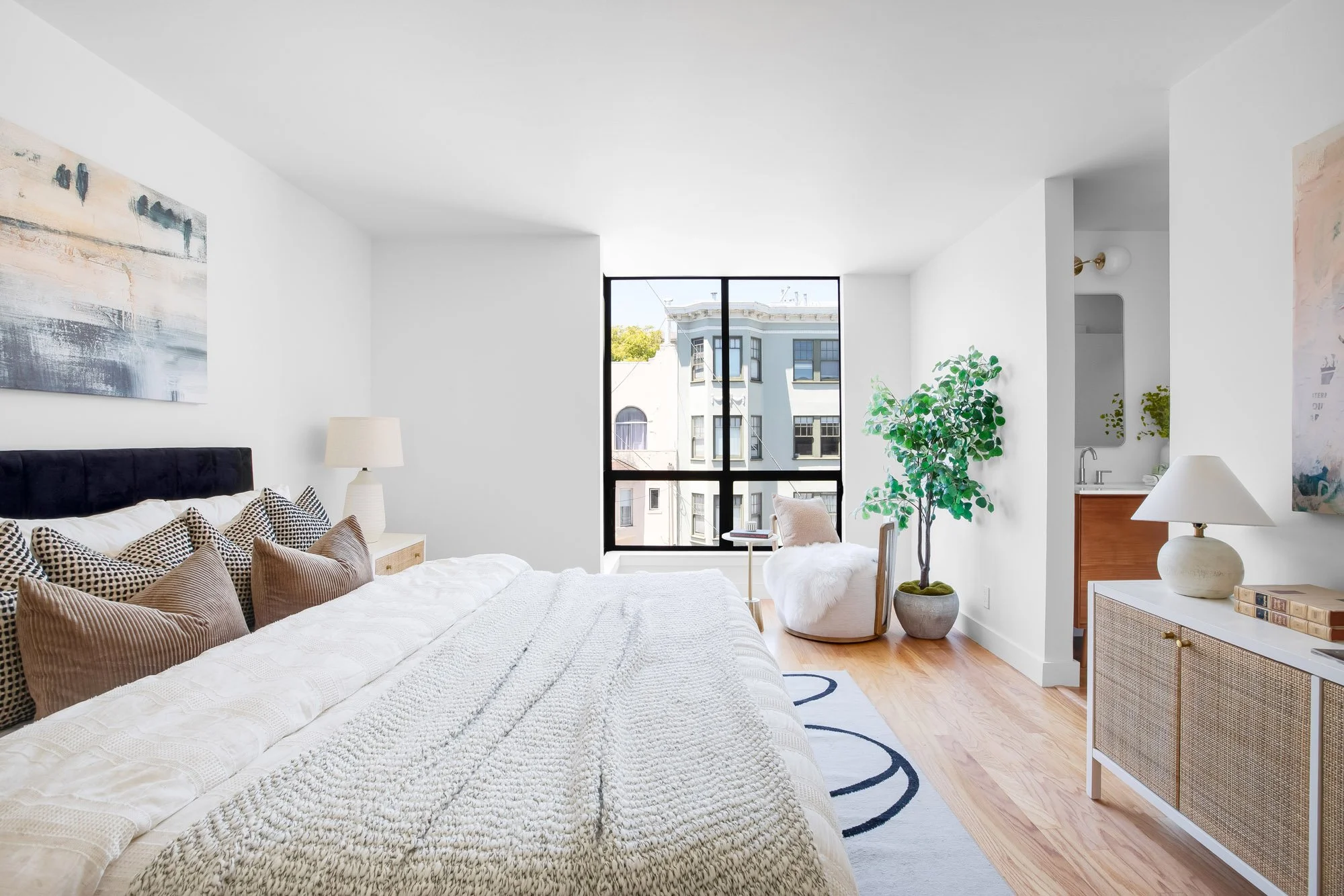 Primary bedroom at 932 Broderick Street #2 with floor-to-ceiling windows, an en-suite bath with dual vanity, and hardwood floors in NoPa, San Francisco.