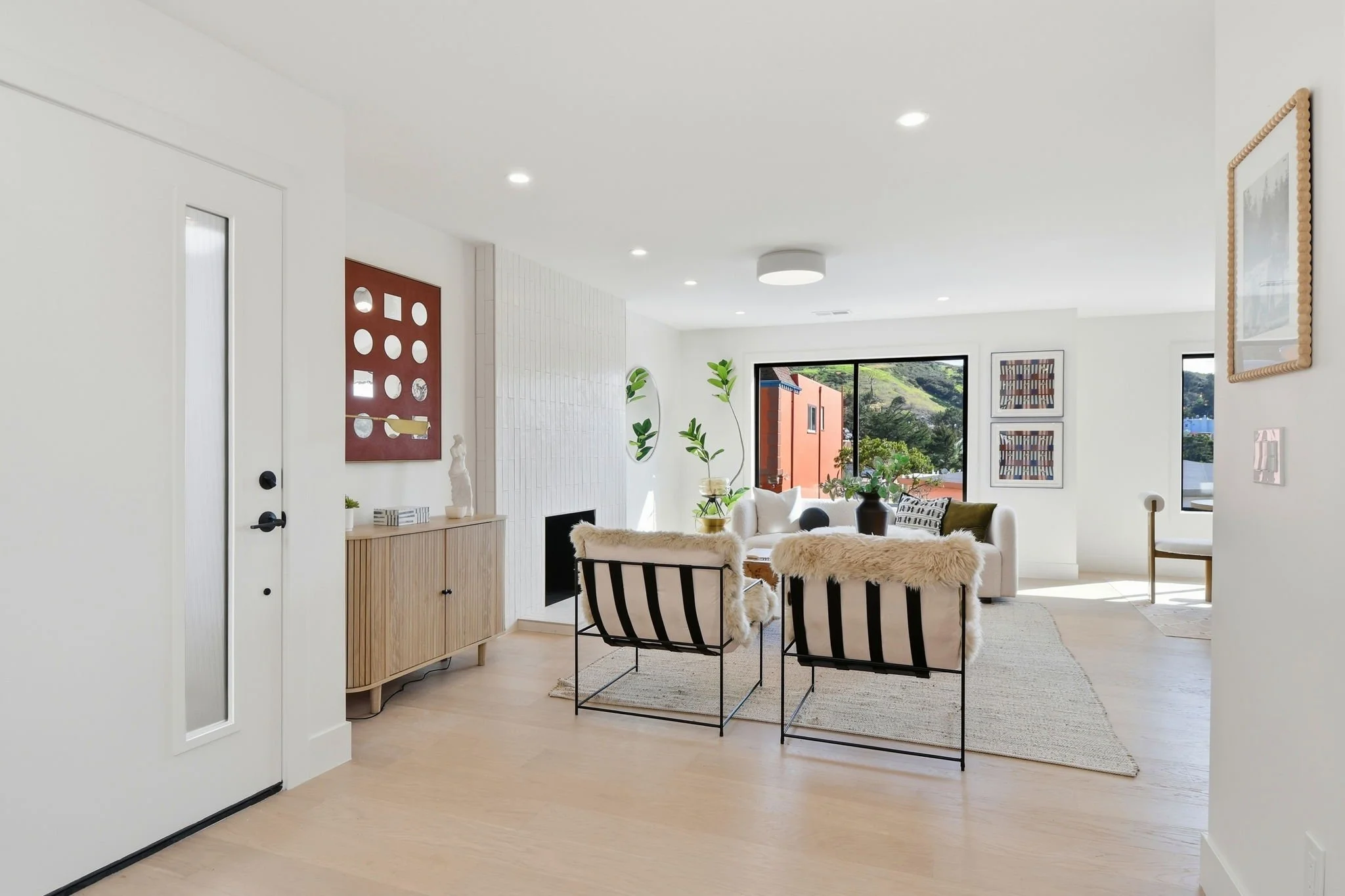 Bright, open-concept living room in a Midtown Terrace residence with white oak hardwood floors, recessed lighting, and designer mid-century modern furniture.
