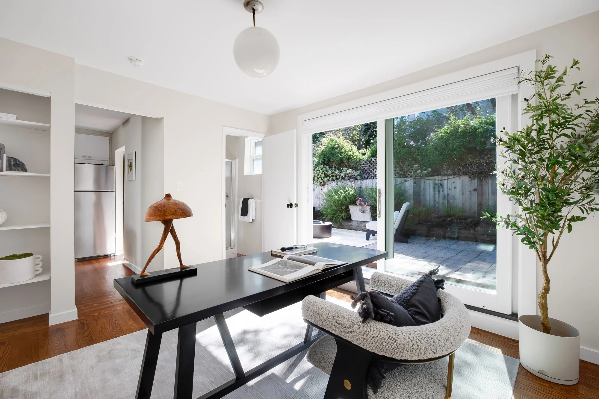 Second living area at 465 30th Street with built-in shelving, hardwood floors, an adjoining bathroom and garden access through a sliding glass door