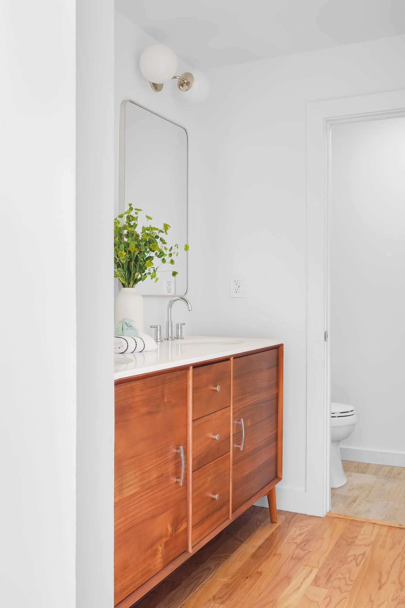 Primary en-suite bathroom at 932 Broderick Street #2 with a mid-century walnut vanity, quartz counter, framed mirror, and a separate water closet.