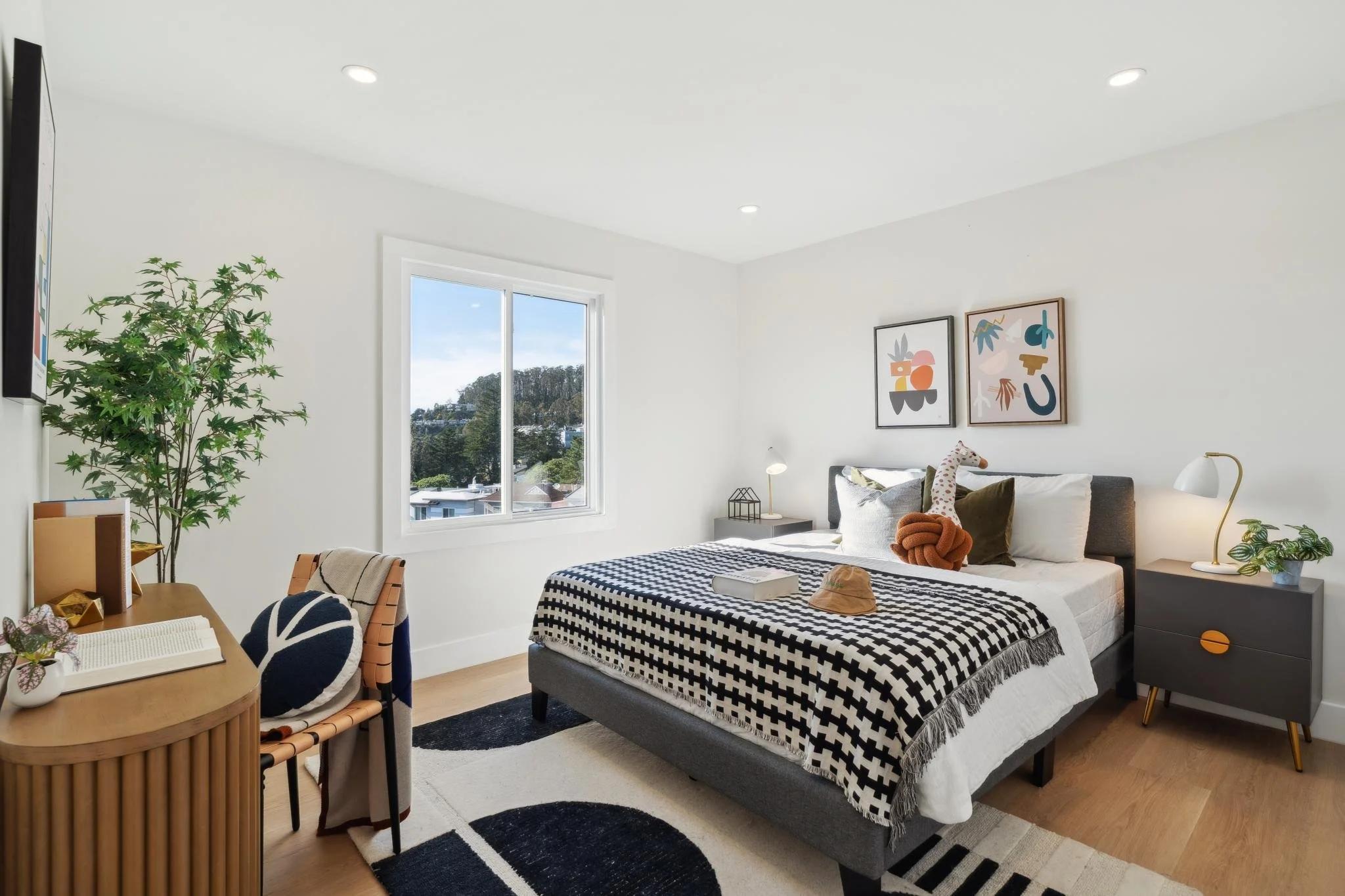 Modern guest bedroom at 147 Gladeview Way featuring a grey platform bed, geometric rug, and a curved wood desk setup perfect for a home office.