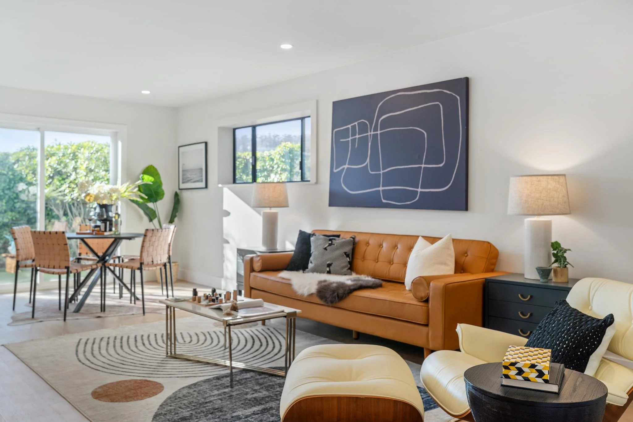 Modern family room featuring a tan leather sofa, mid-century modern lounge chair, and a sliding glass door leading to a private backyard in San Francisco.
