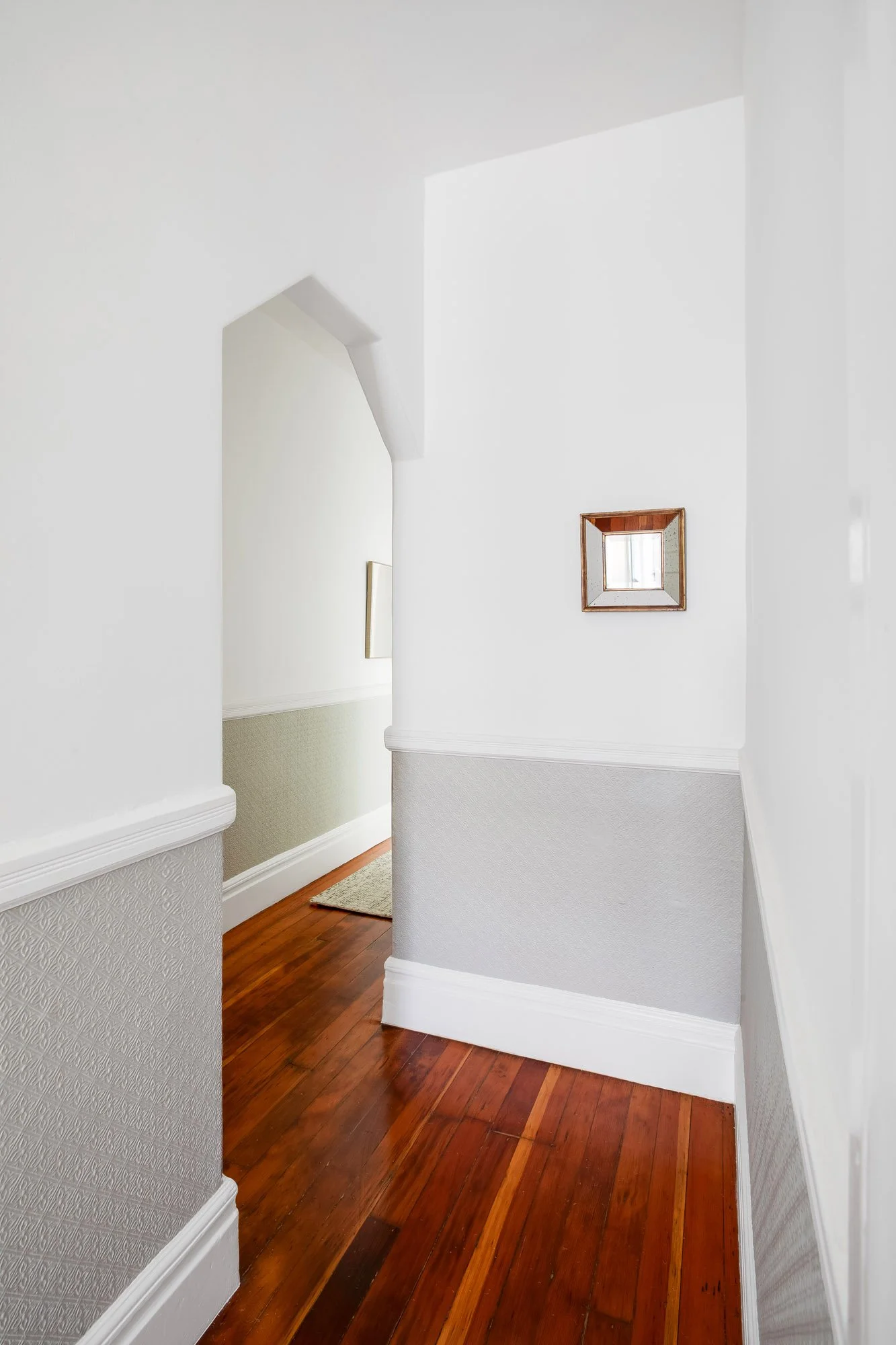 Hallway with lincrusta wainscotting and an archway leading toward the bedrooms