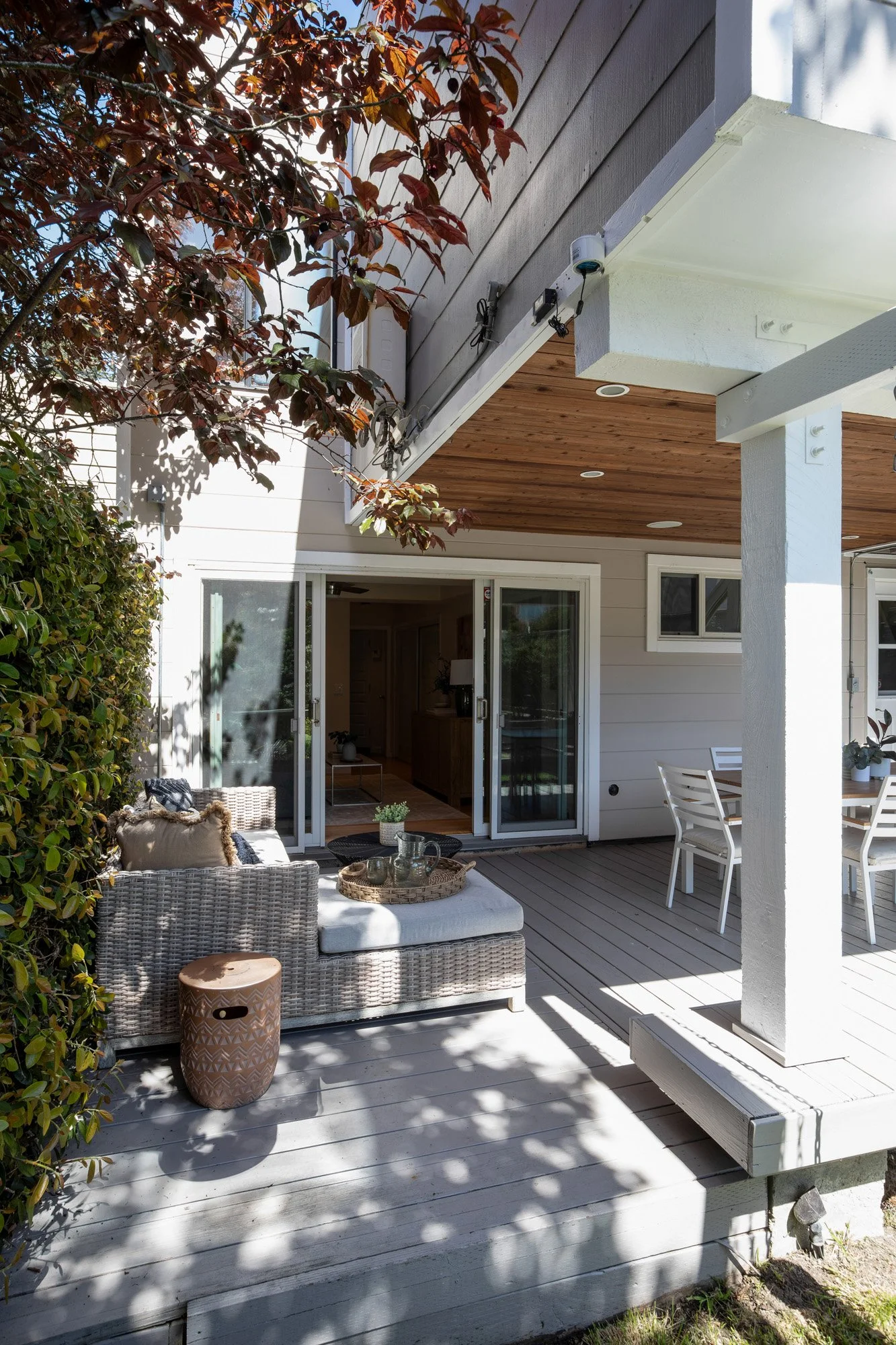 Under-deck patio featuring a modern outdoor sectional sofa with decorative pillows and a natural wood ceiling.