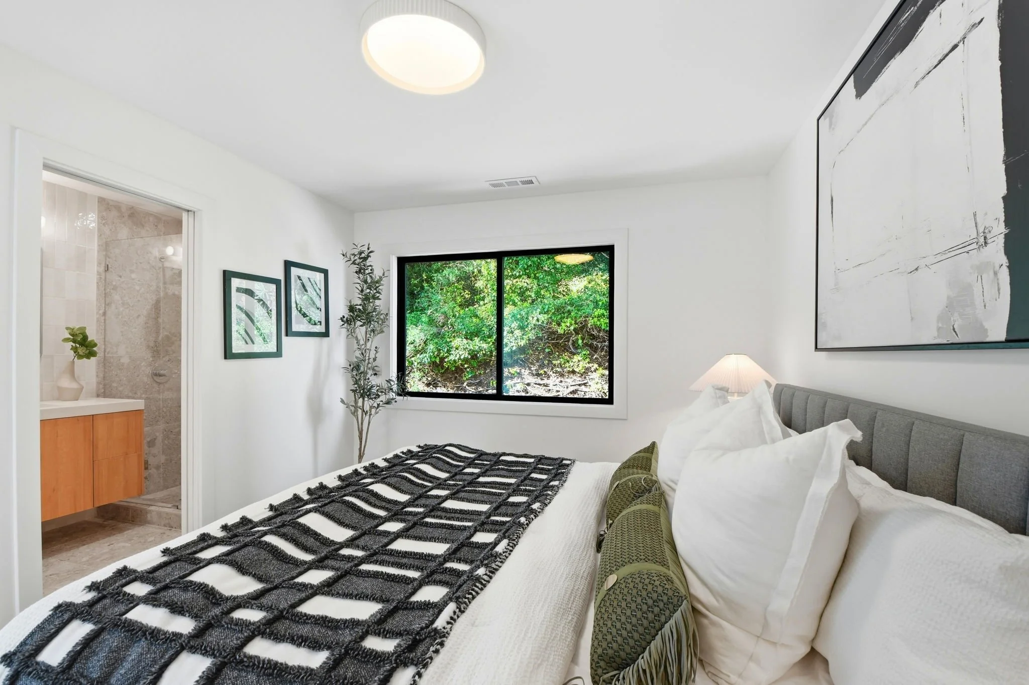 Luxury primary bedroom with a view into the renovated ensuite bathroom featuring a custom wood vanity and natural stone walk-in shower.