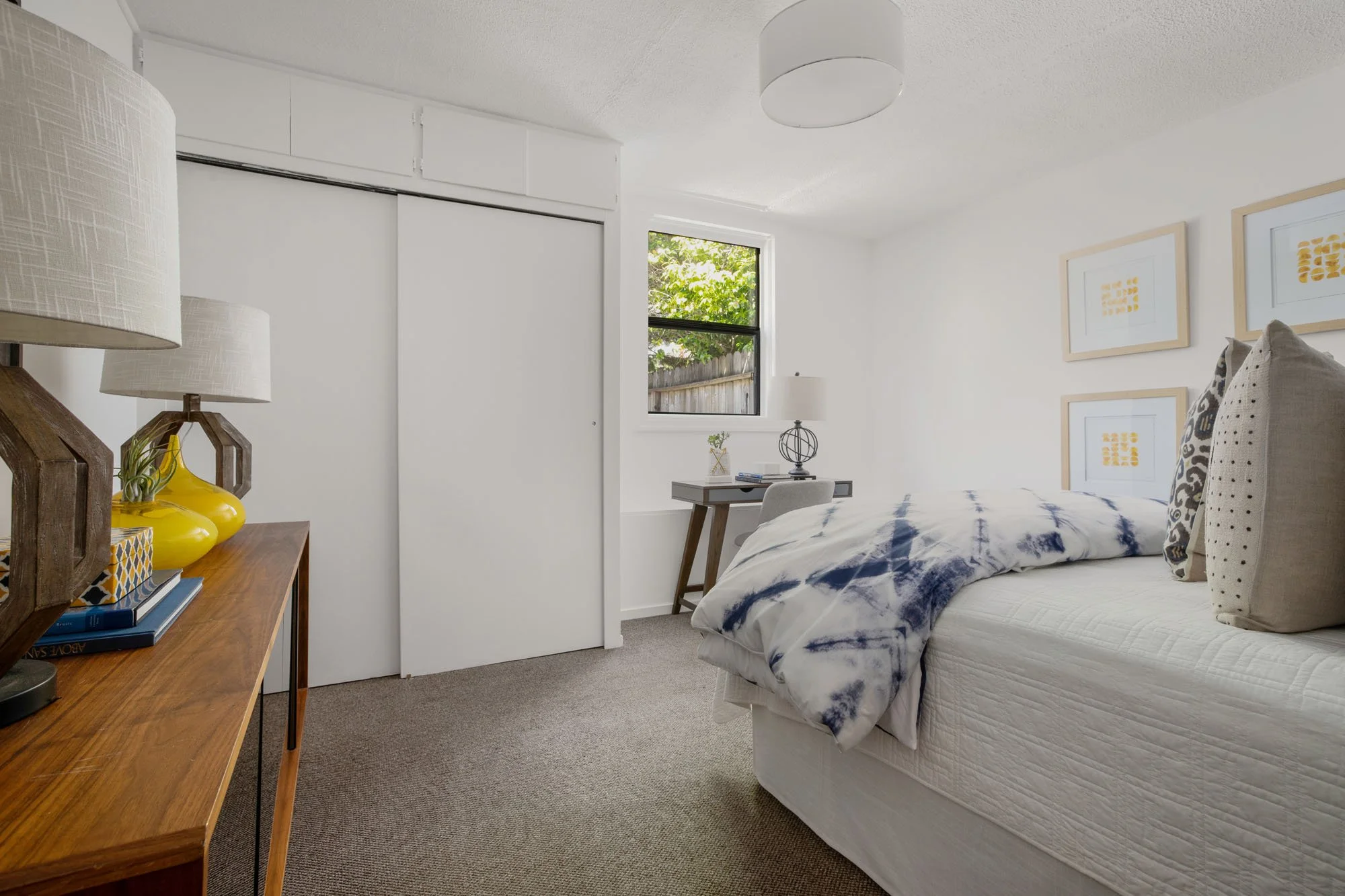 Secondary bedroom with plush carpeting, a built-in closet, and a dedicated workspace area with natural window light.