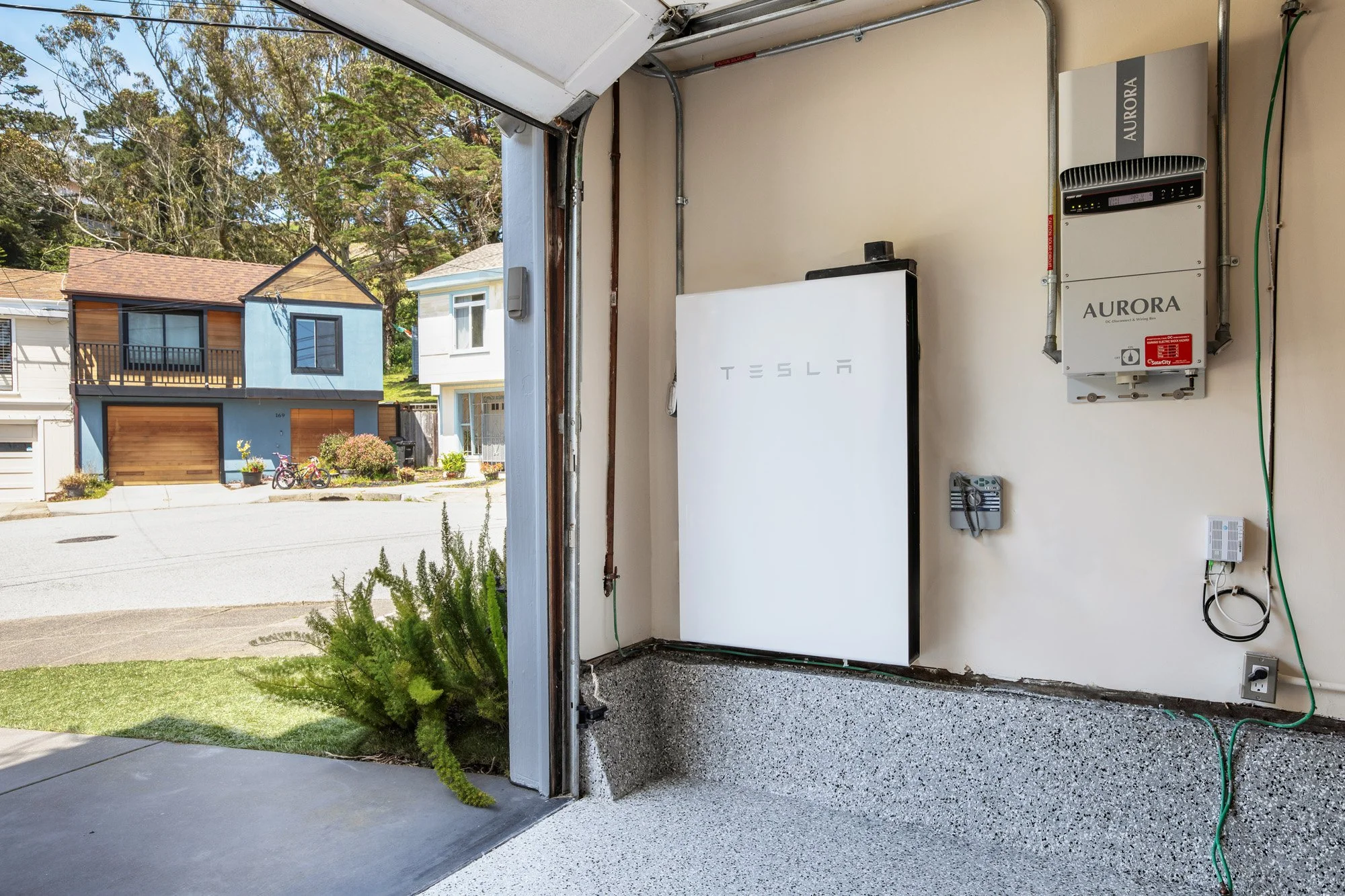 EV-ready garage featuring a Tesla Powerwall and Aurora solar inverter, showing sustainable energy integration and smart home features.