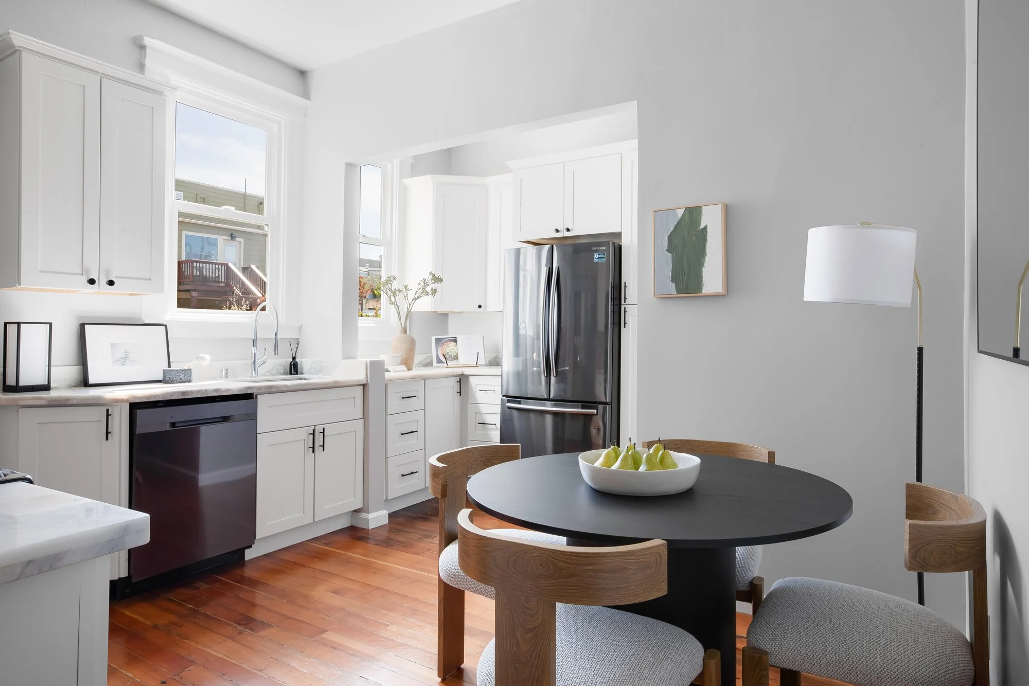 Kitchen with white shaker cabinets, marble counters, and a round eat-in dining table