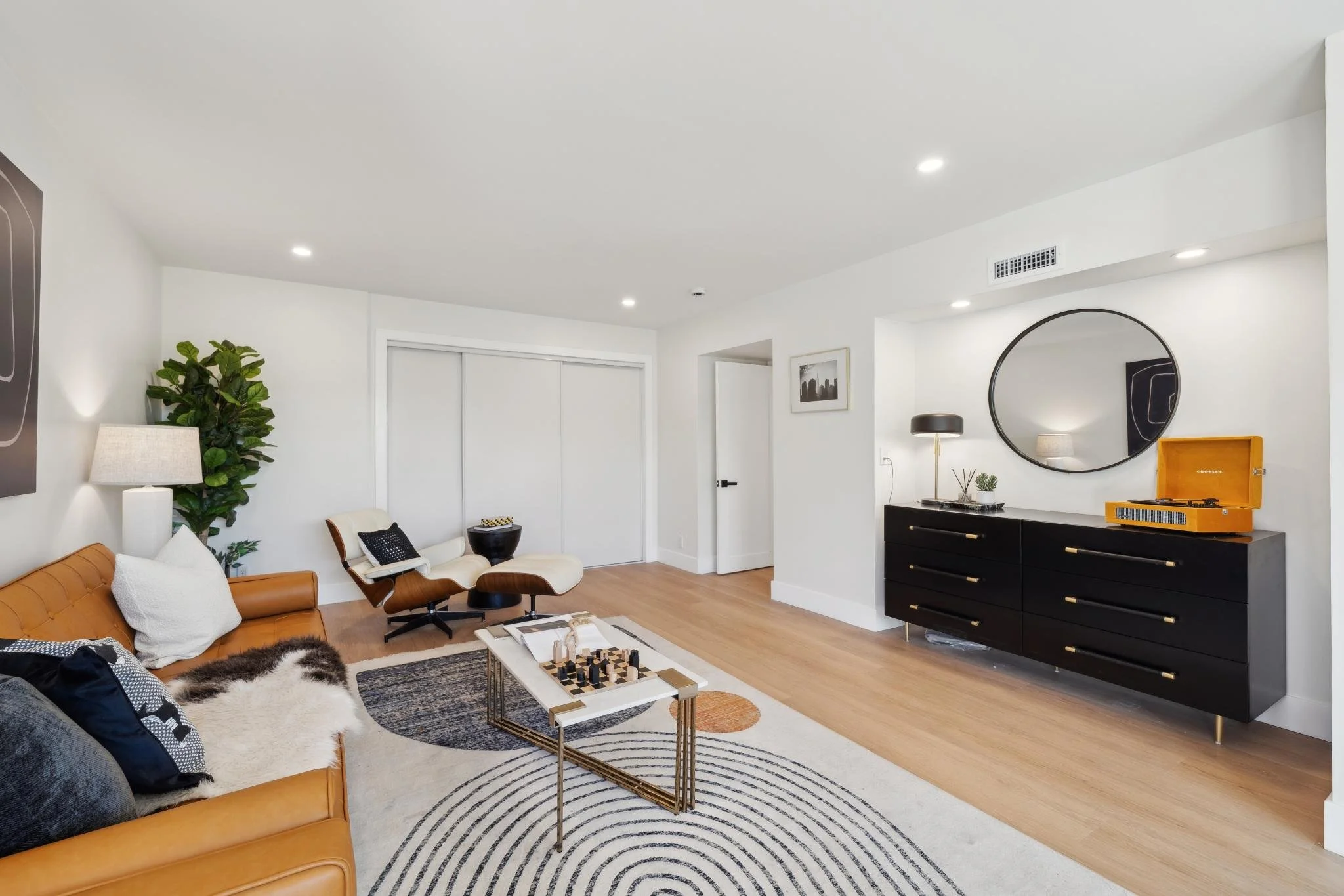 Spacious secondary living area with a white marble coffee table, geometric rug, and minimalist sliding closet doors for extra storage.