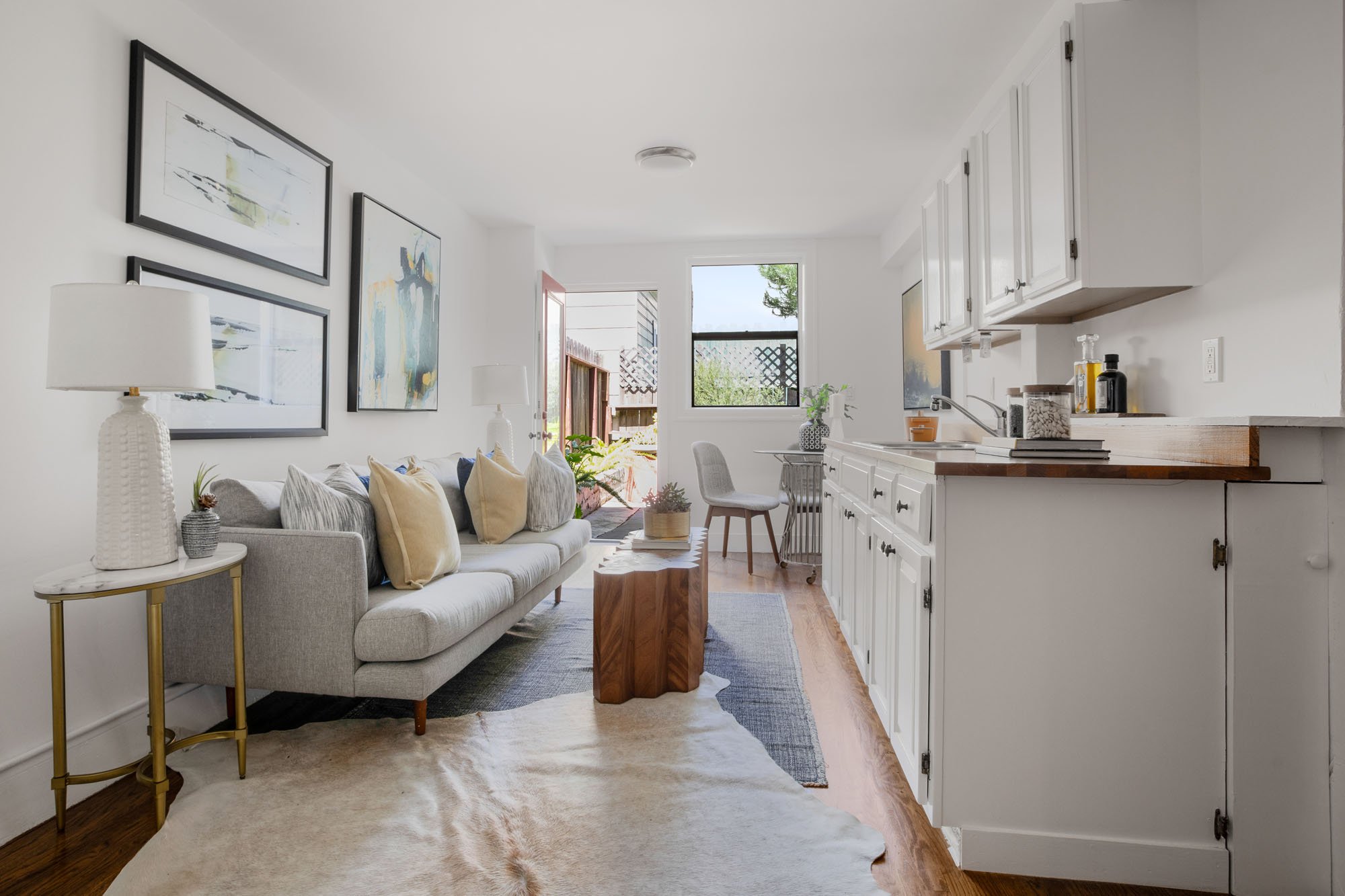 Sun-drenched garden-level living area with white cabinetry, modern seating, and direct access to a private backyard.