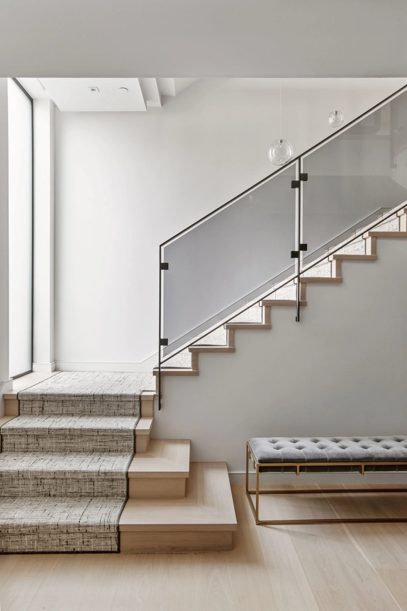 Minimalist staircase design at 1647 Sanchez showcasing the home's clean lines, light hardwood floors, and designer glass railings.