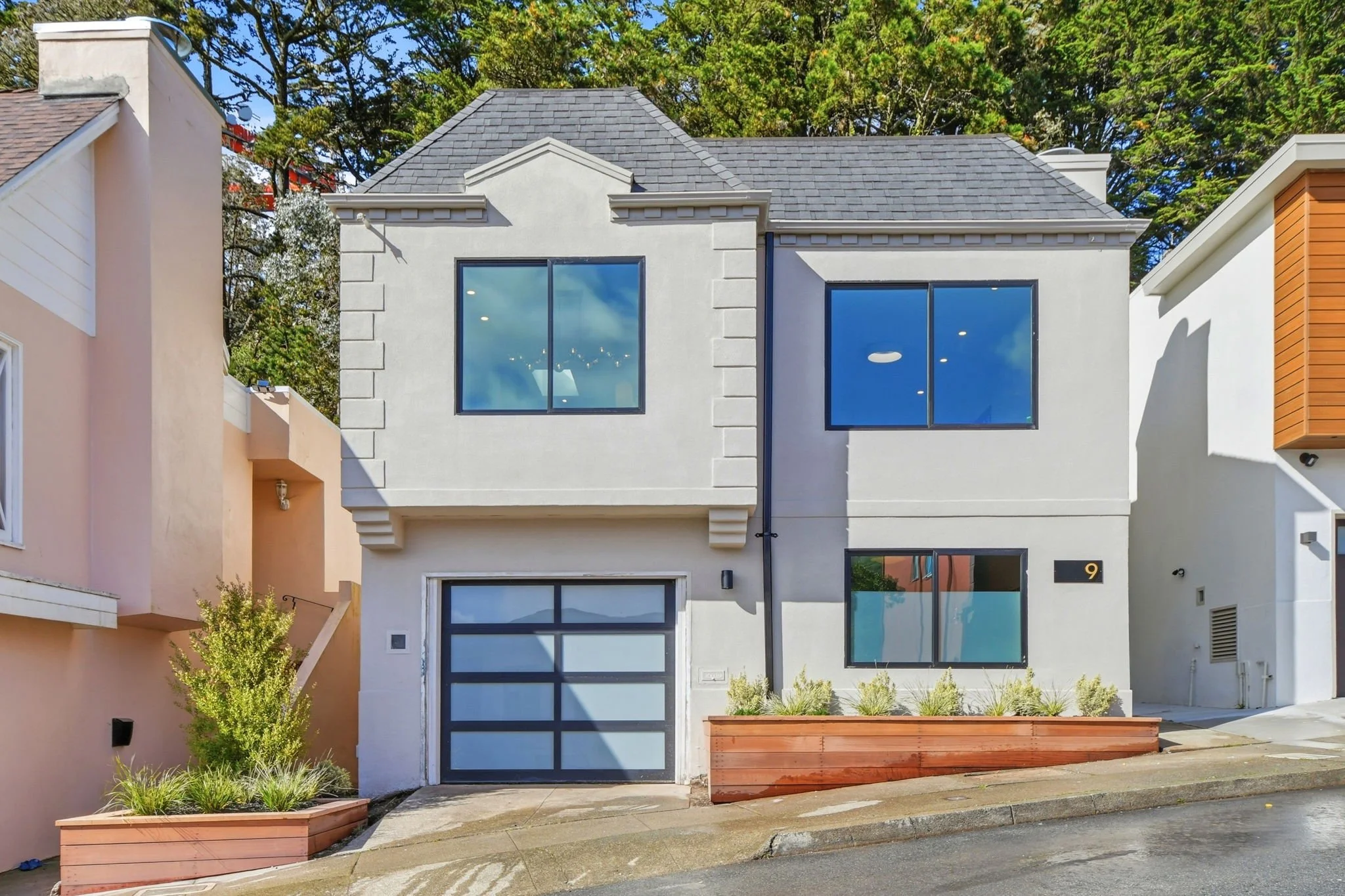 Modern luxury home facade in Midtown Terrace, San Francisco, featuring a contemporary white exterior, black-trimmed windows, and custom wood planter boxes with drought-tolerant plants.