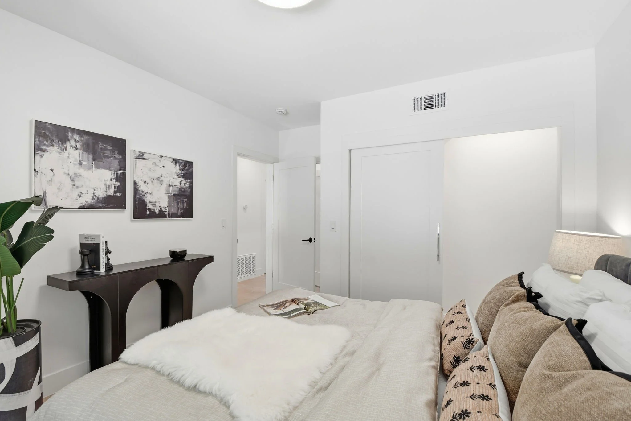 Designer bedroom detail highlighting a sculptural dark wood console table and light oak floors in a luxury San Francisco residence.