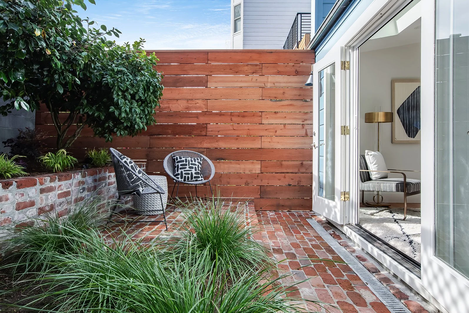 Secluded brick-paved patio with a modern horizontal wood fence and manicured garden beds, perfect for urban outdoor living.