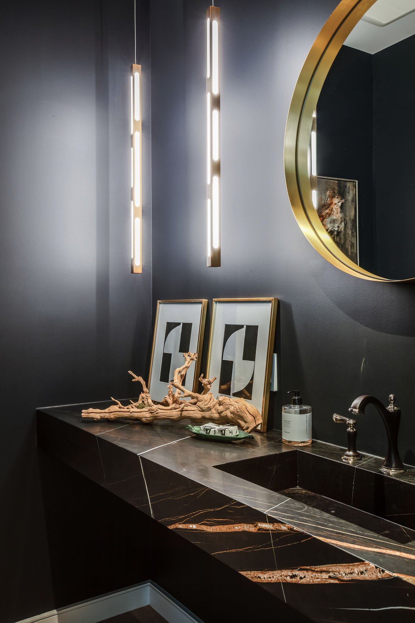 Moody designer powder room at 1647 Sanchez with a black marble integrated sink, gold circular mirror, and modern vertical tube pendant lighting.