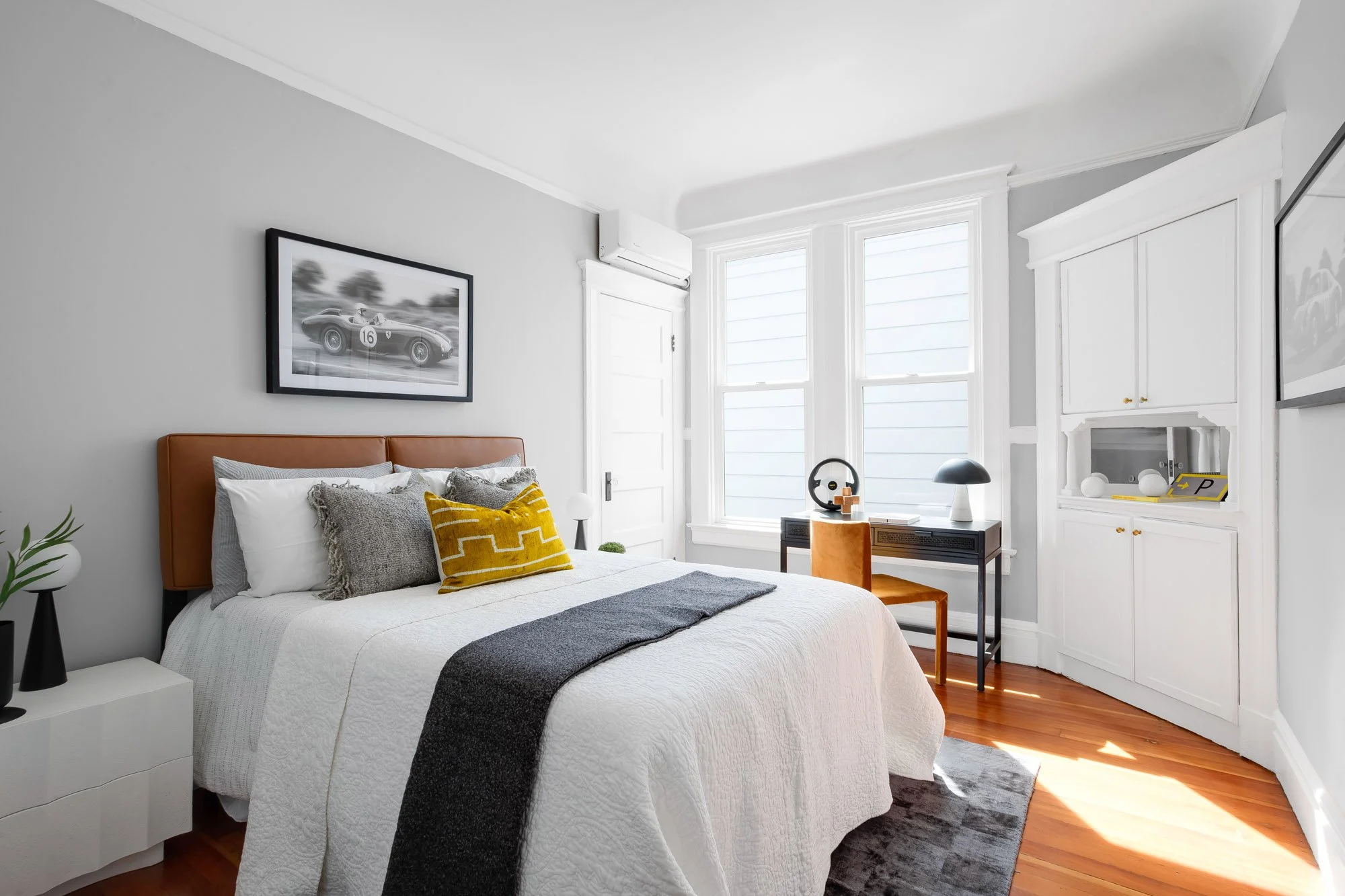 Primary bedroom with tan leather headboard, built-in corner cabinet, and mini-split heating and cooling
