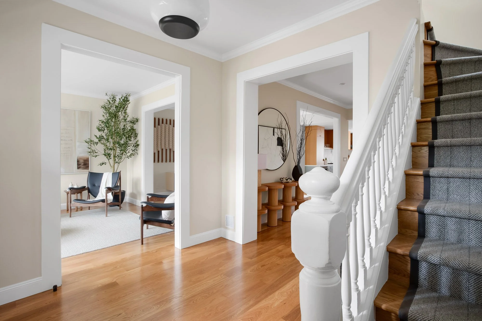 Central stair hall at 771 Elizabeth Street in Noe Valley with a restored Edwardian staircase, custom wool runner, turned white balusters, and wide cased openings framing the living and sitting rooms.