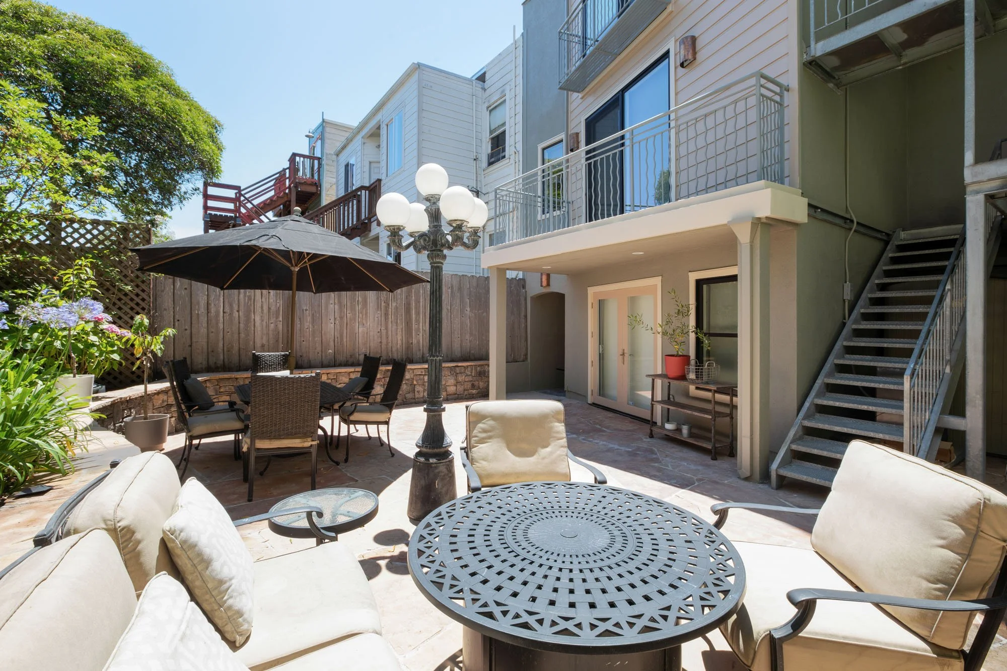 Private outdoor patio with flagstone pavers, a luxury dining set with a black umbrella, and a decorative vintage-style street lamp.