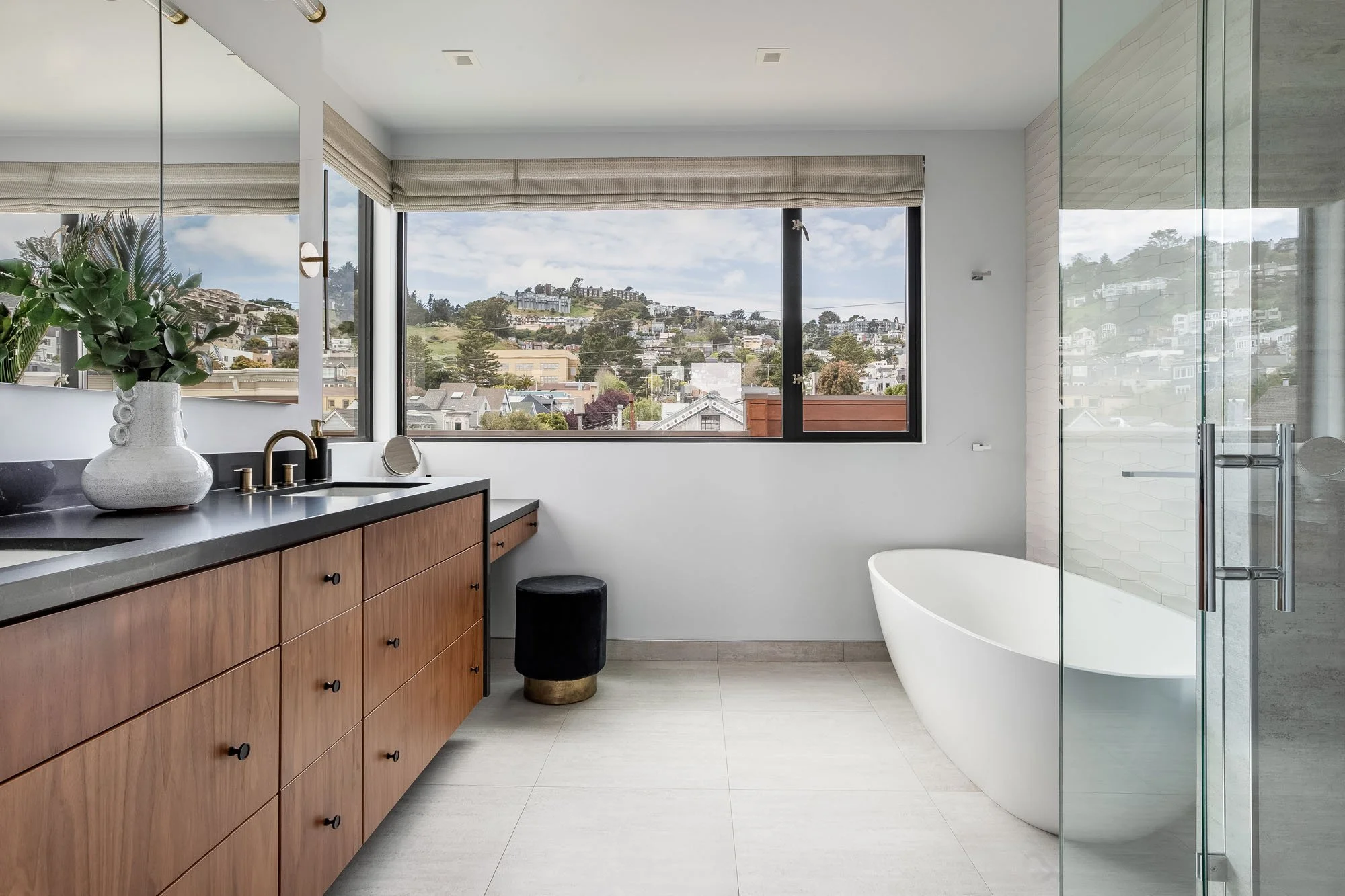 Luxury primary bathroom at 1647 Sanchez featuring a custom walnut double vanity, freestanding soaking tub, and large windows with views of the San Francisco hills.