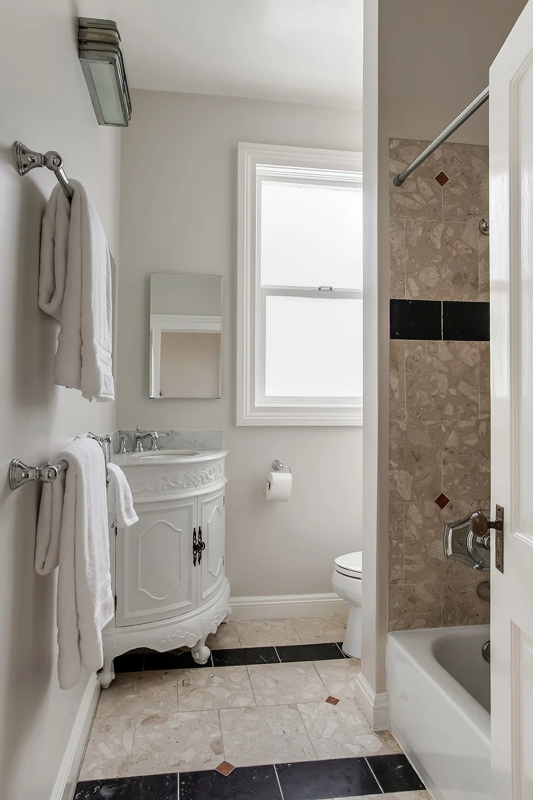 Classic San Francisco bathroom featuring an ornate white marble-top vanity and period-appropriate terrazzo tile flooring with black accents.