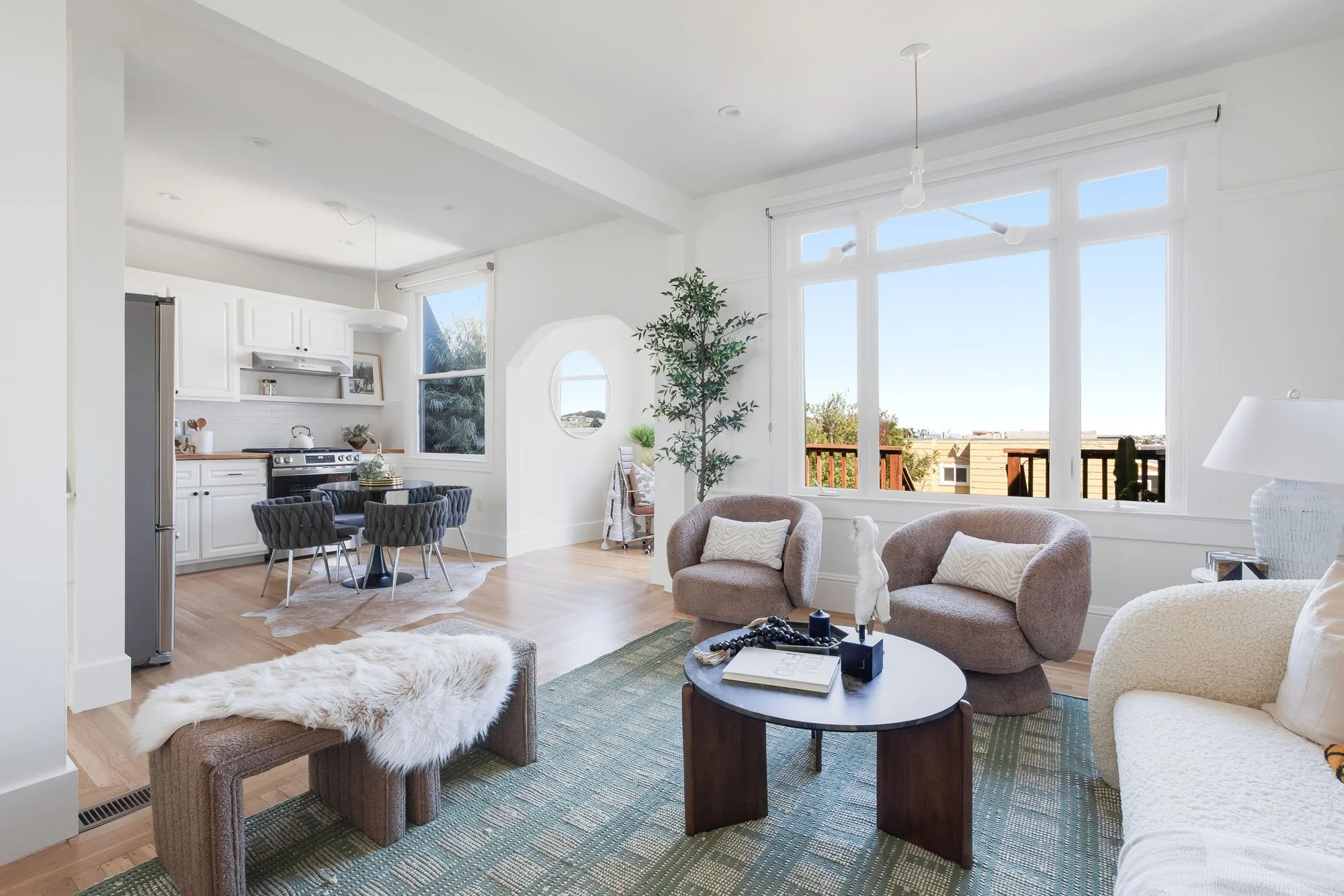 A wide-angle view of the continuous living, dining, and kitchen area, highlighting the hardwood floors and the airy, bright layout of the home.