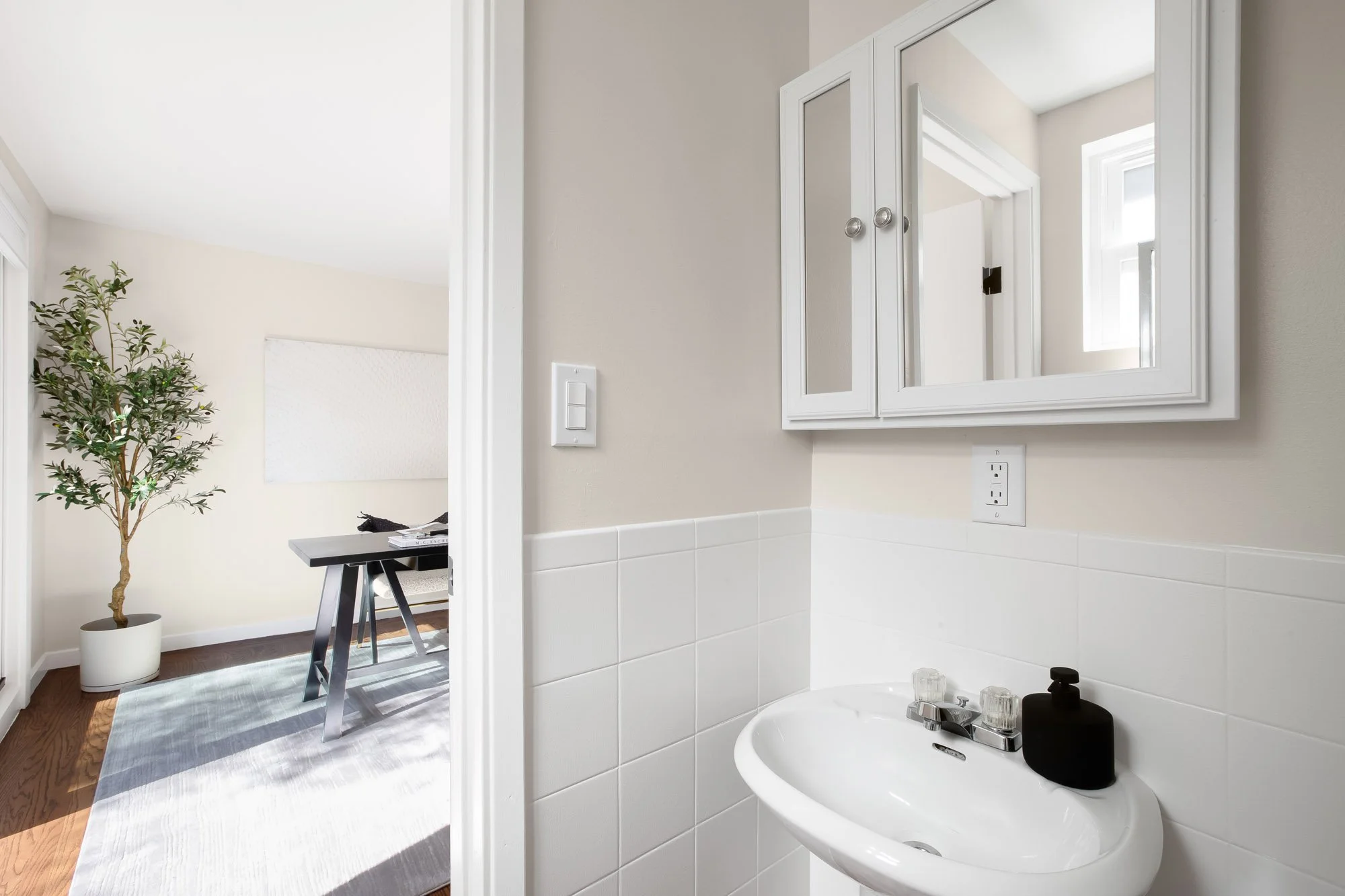 Second bathroom at 465 30th Street with a pedestal sink, white tile wainscot and medicine cabinet, adjoining the second living area
