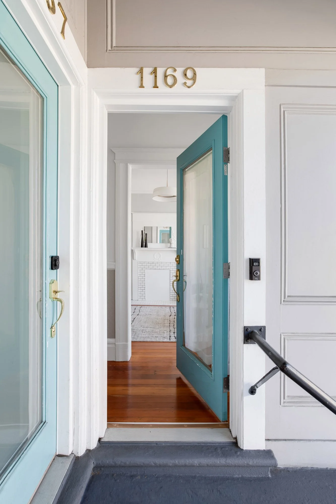 Front door at 1169 Alabama Street, open to a hallway with original hardwood floors and a painted fireplace mantel beyond
