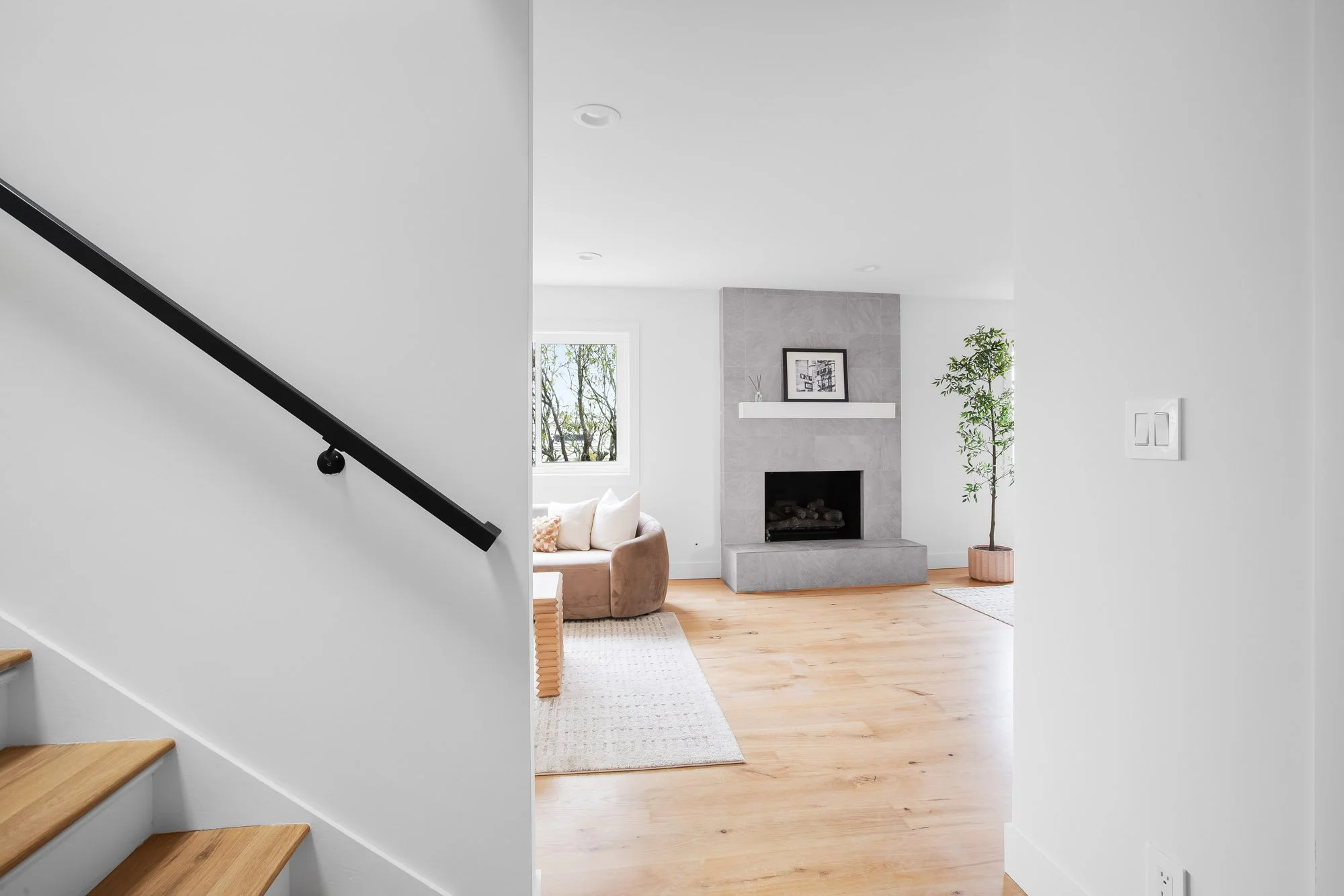 Living room at 75 Aloha Avenue in Golden Gate Heights, seen from the stair, with a gray tile-surround gas fireplace and refinished oak floors.