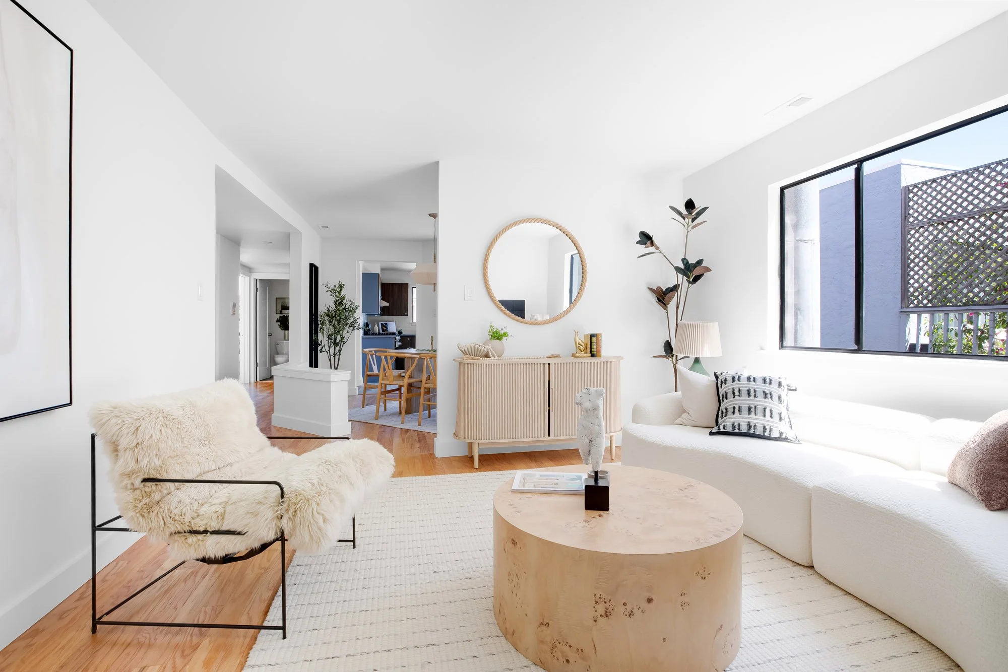 Open-concept living room at 932 Broderick Street #2 with sightlines to the dining area and renovated kitchen, lit by a large window with hardwood floors throughout.