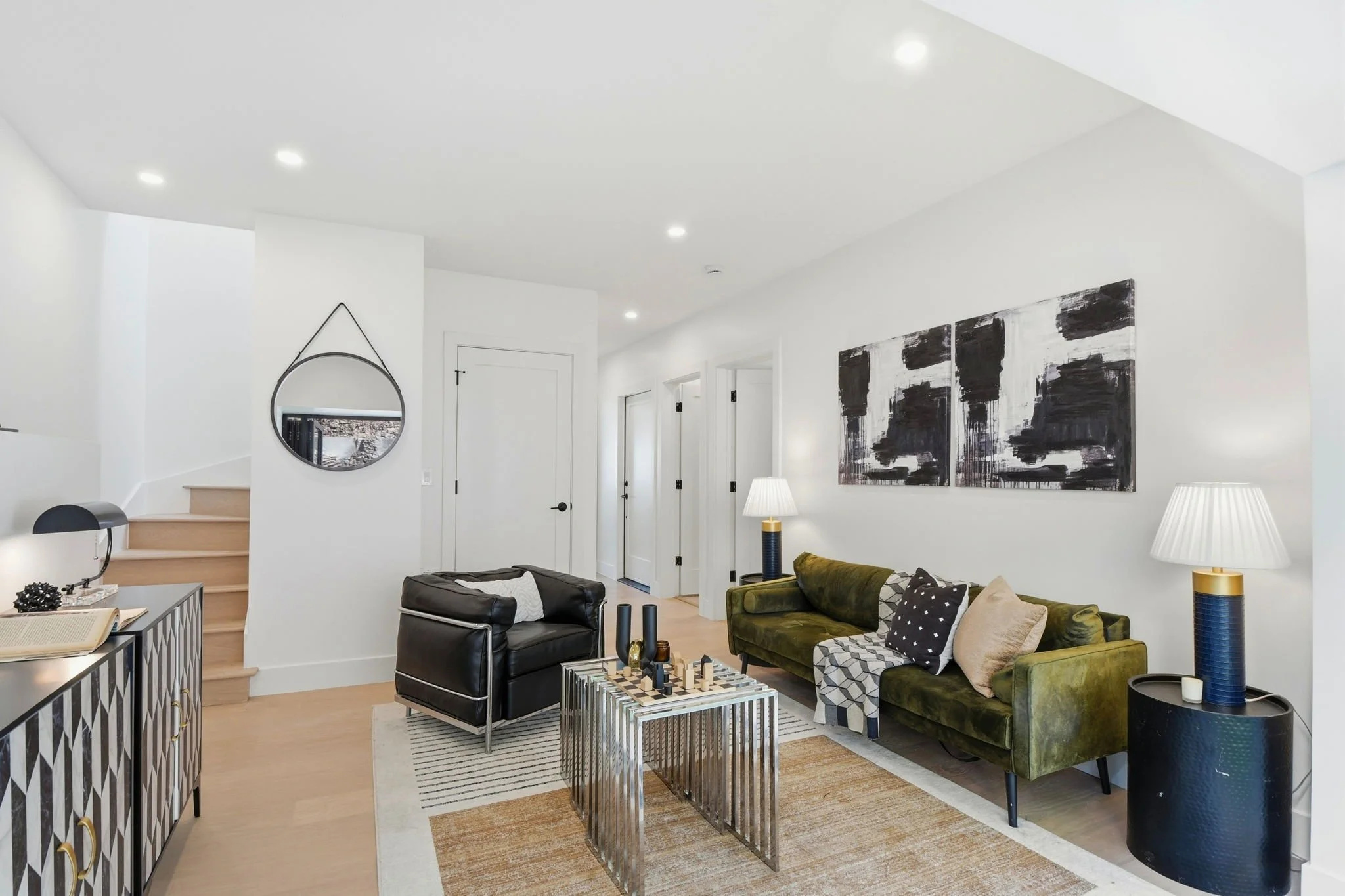 Stylish lower-level family room or guest lounge with a green velvet sofa, abstract art, and contemporary lighting in a renovated Midtown Terrace home.