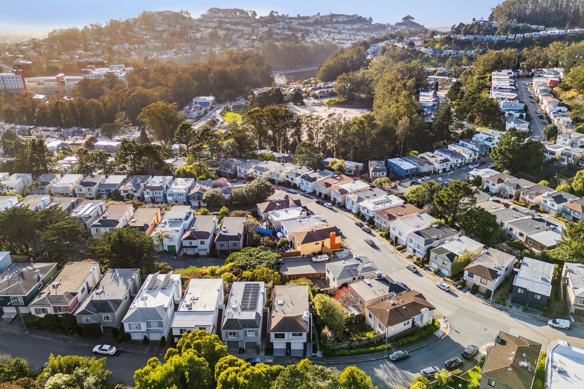 High-altitude drone view of the Twin Peaks/Diamond Heights area, showing the residential street layout and the surrounding forest canopy.