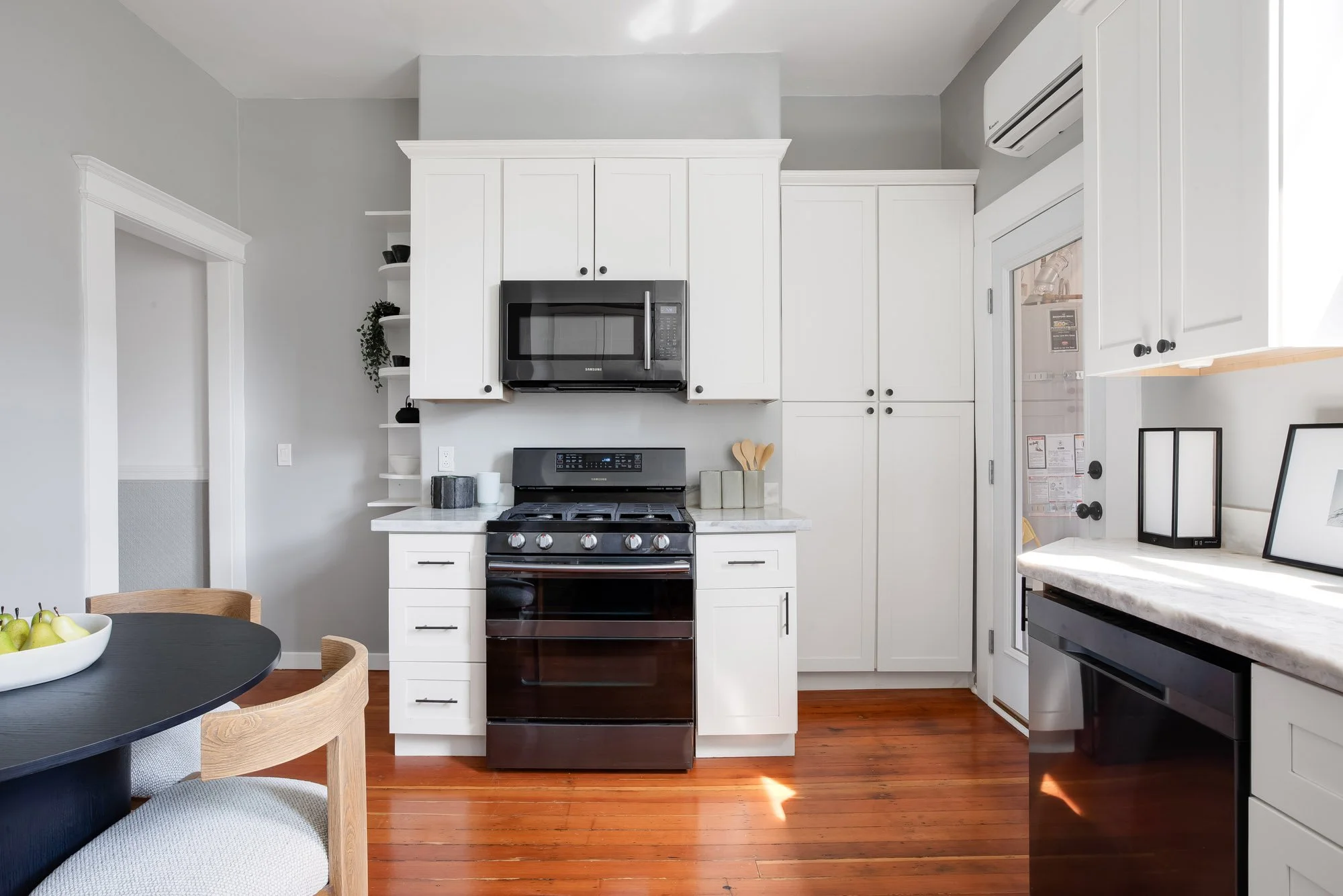 Kitchen range wall with marble counters, white shaker cabinetry, and open shelving