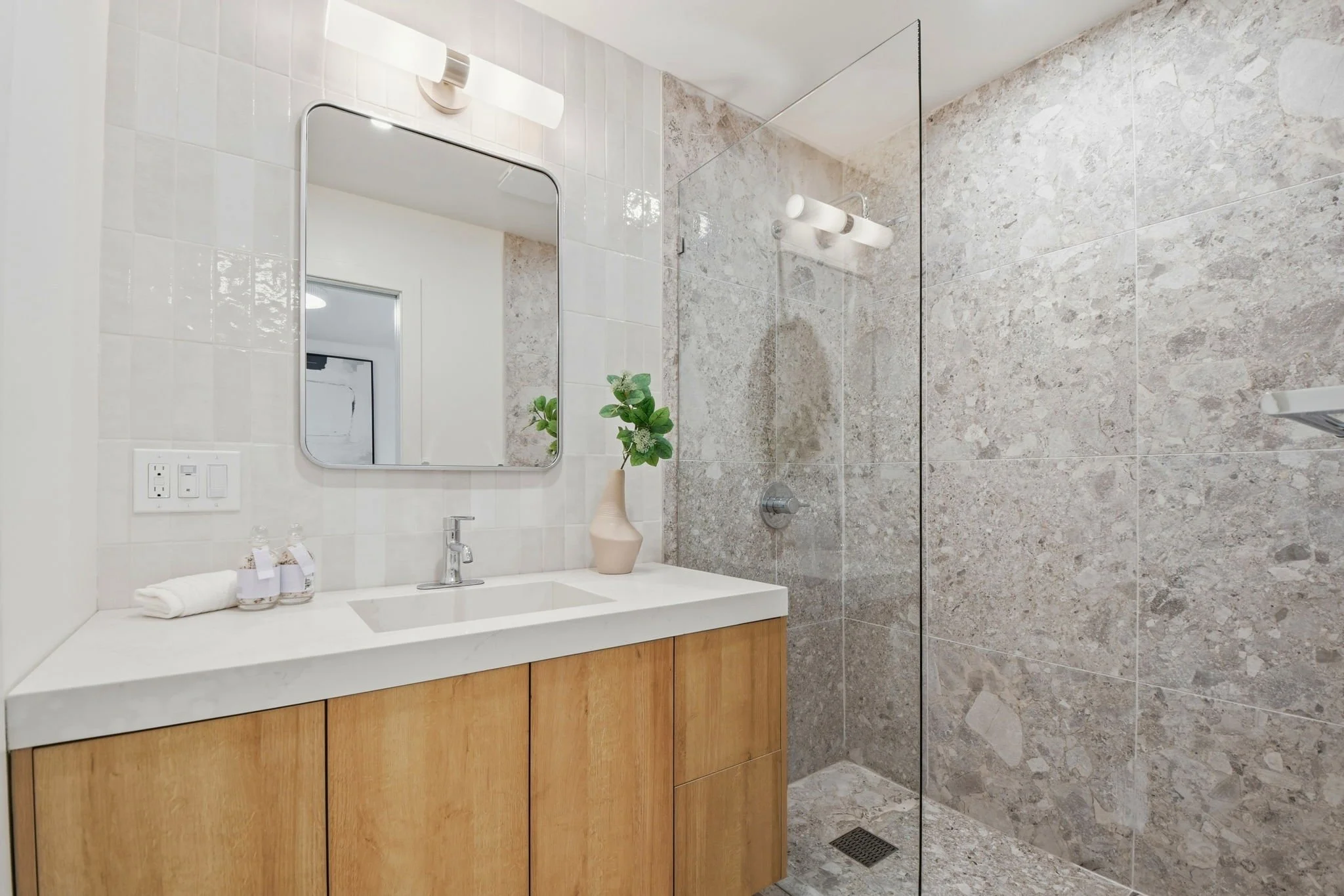 Modern bathroom detail highlighting a walk-in shower with large-format gray tiles and contemporary gold shower hardware.