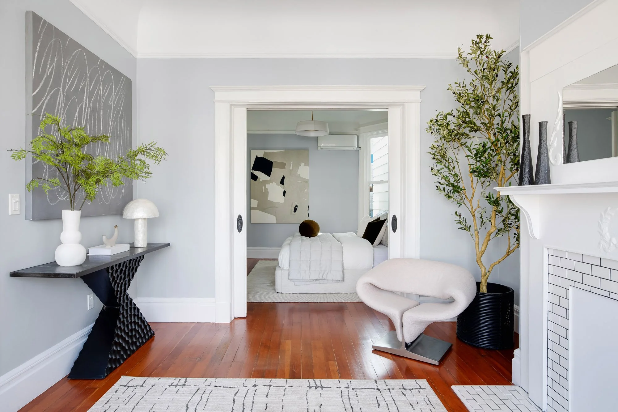 Hallway view toward the guest bedroom through open pocket doors, with the living room fireplace at right