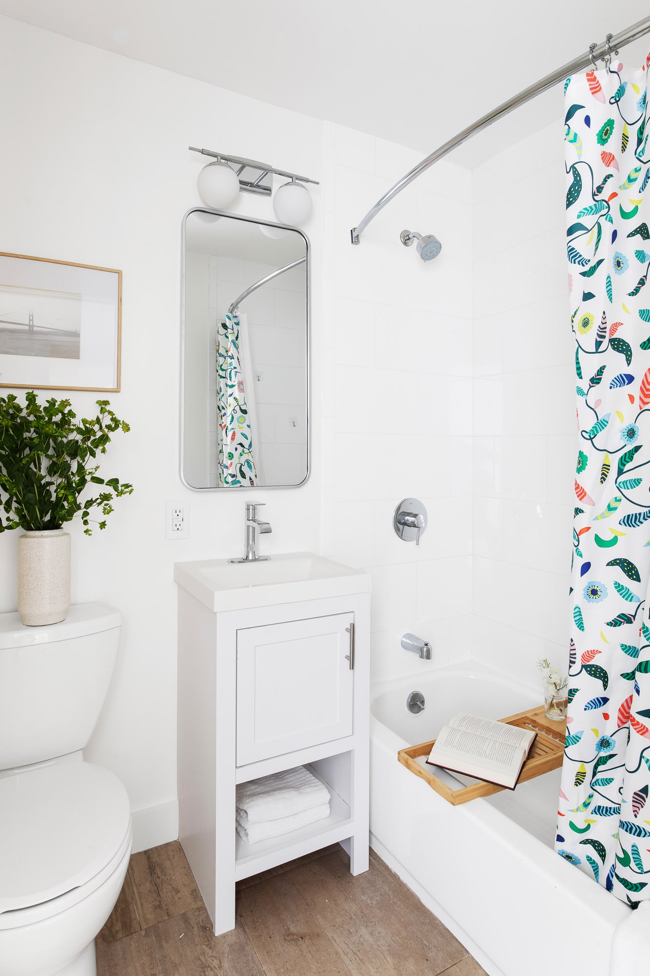 Refreshed hall bathroom at 932 Broderick Street #2 with a white vanity, framed mirror, and a tiled tub-and-shower combination.