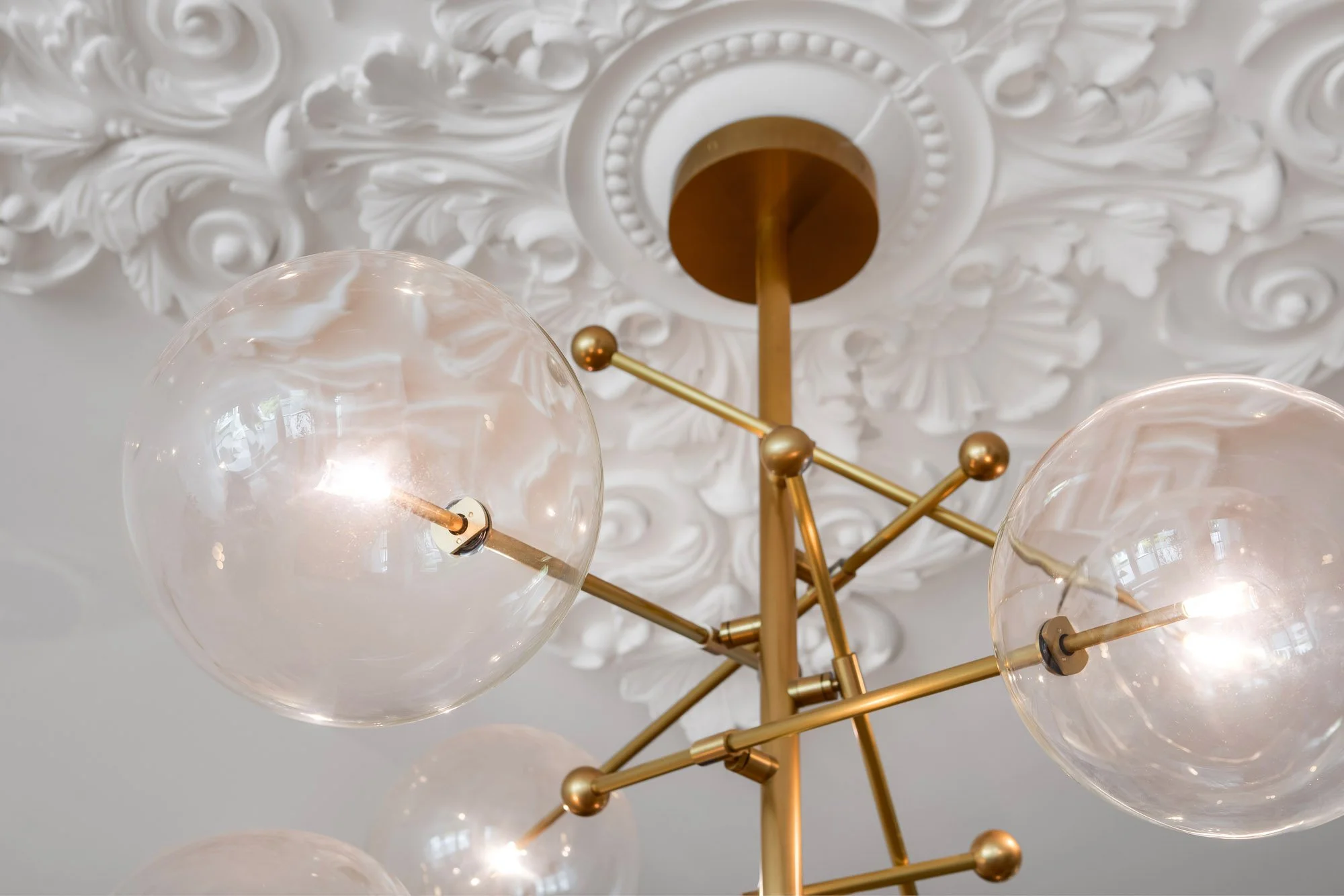 Close-up detail of brass Sputnik chandelier with clear globe shades against ornate Victorian plaster ceiling medallion with acanthus leaf motif in 4545 18th Street San Francisco luxury TIC