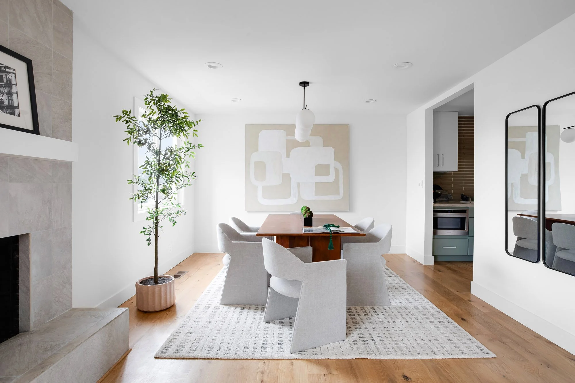 Dining area at 75 Aloha Avenue, San Francisco, on the semi-open main level, with a tiled gas fireplace and the sage-green kitchen beyond.